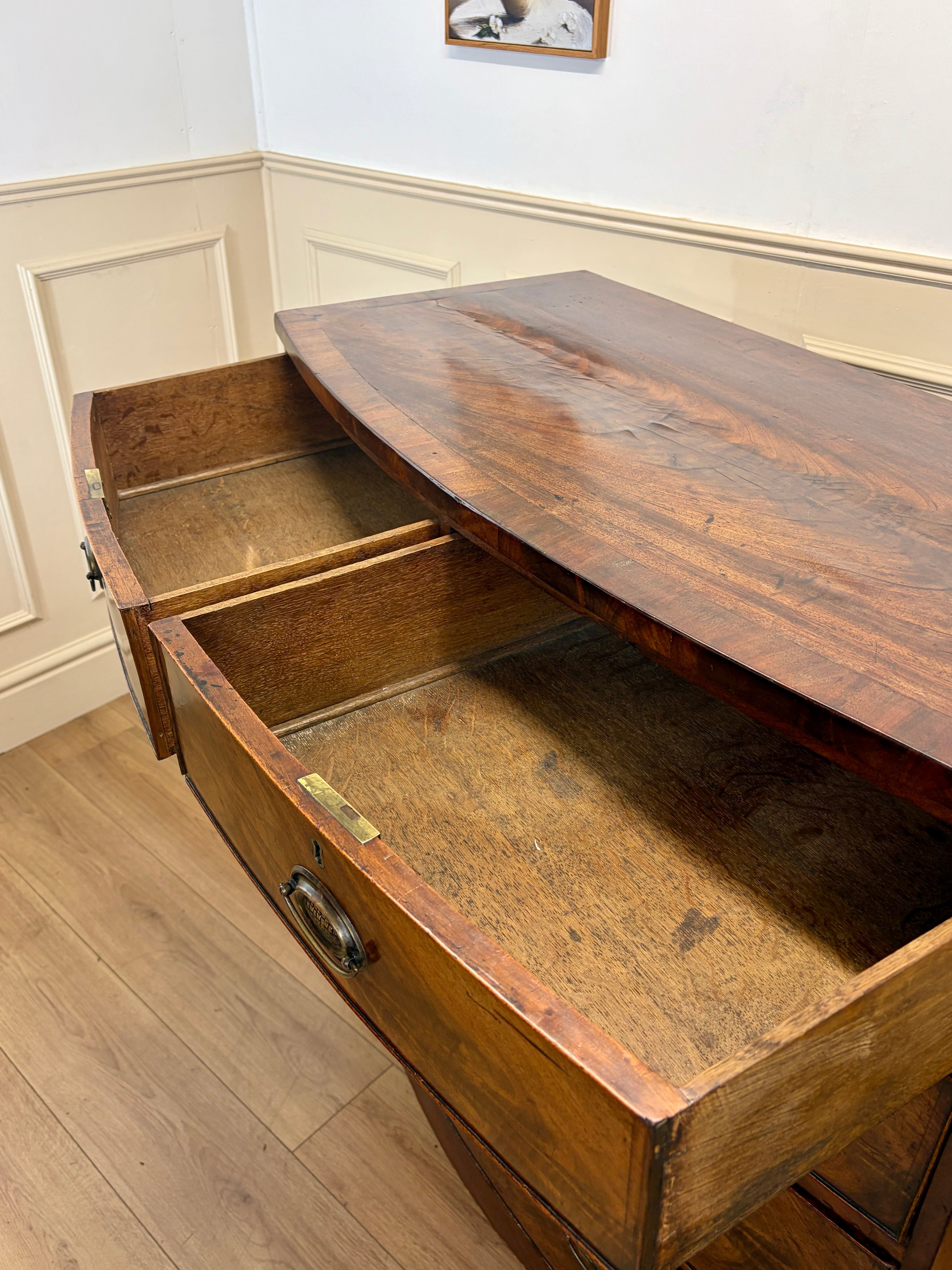 Wooden desk with open drawers in a room with white walls and wooden floor.