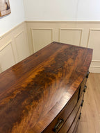 Wooden dresser with a prominent grain pattern in a room with panelled walls.