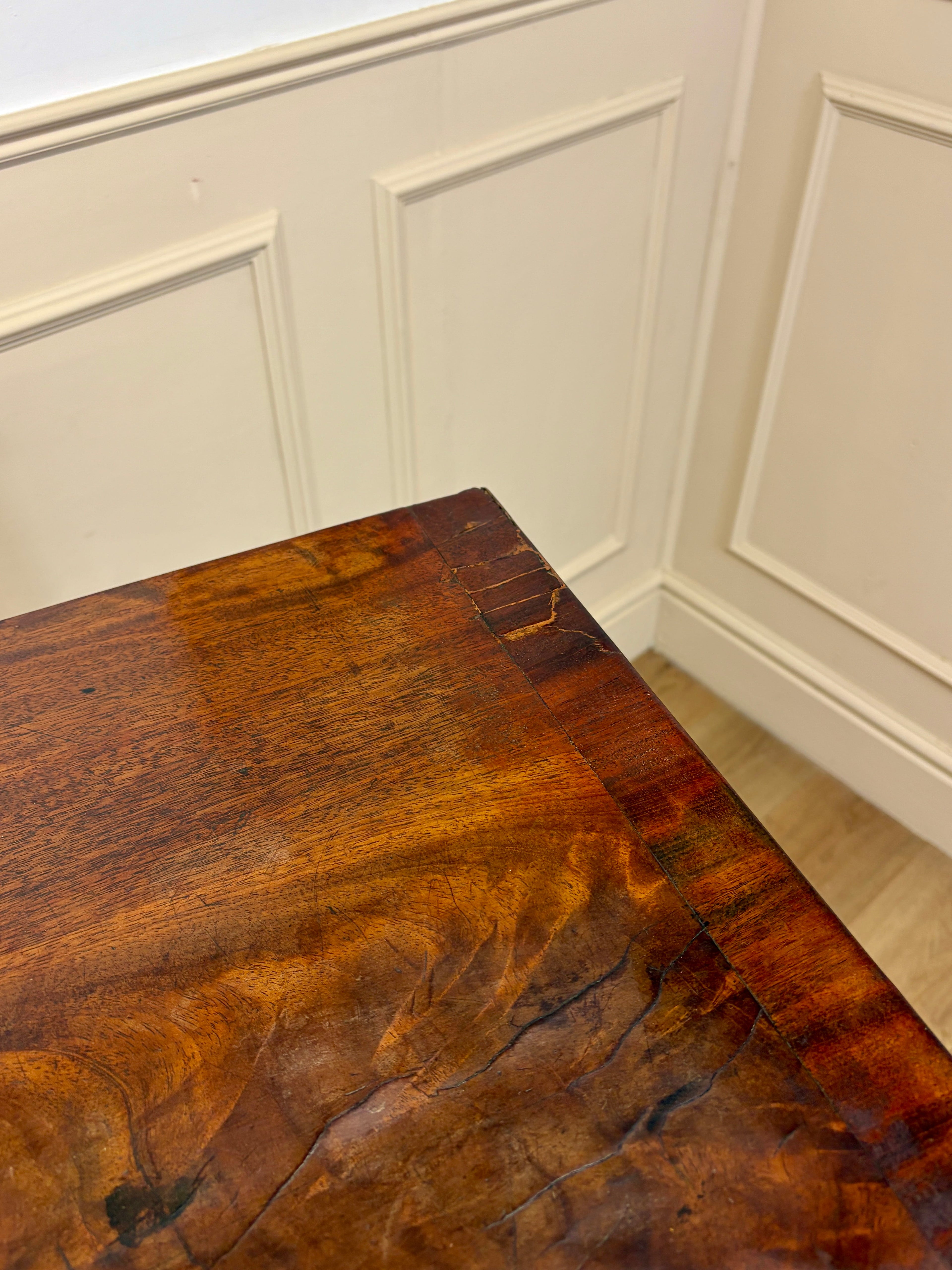 Close-up of a wooden table with wainscoted walls in the background