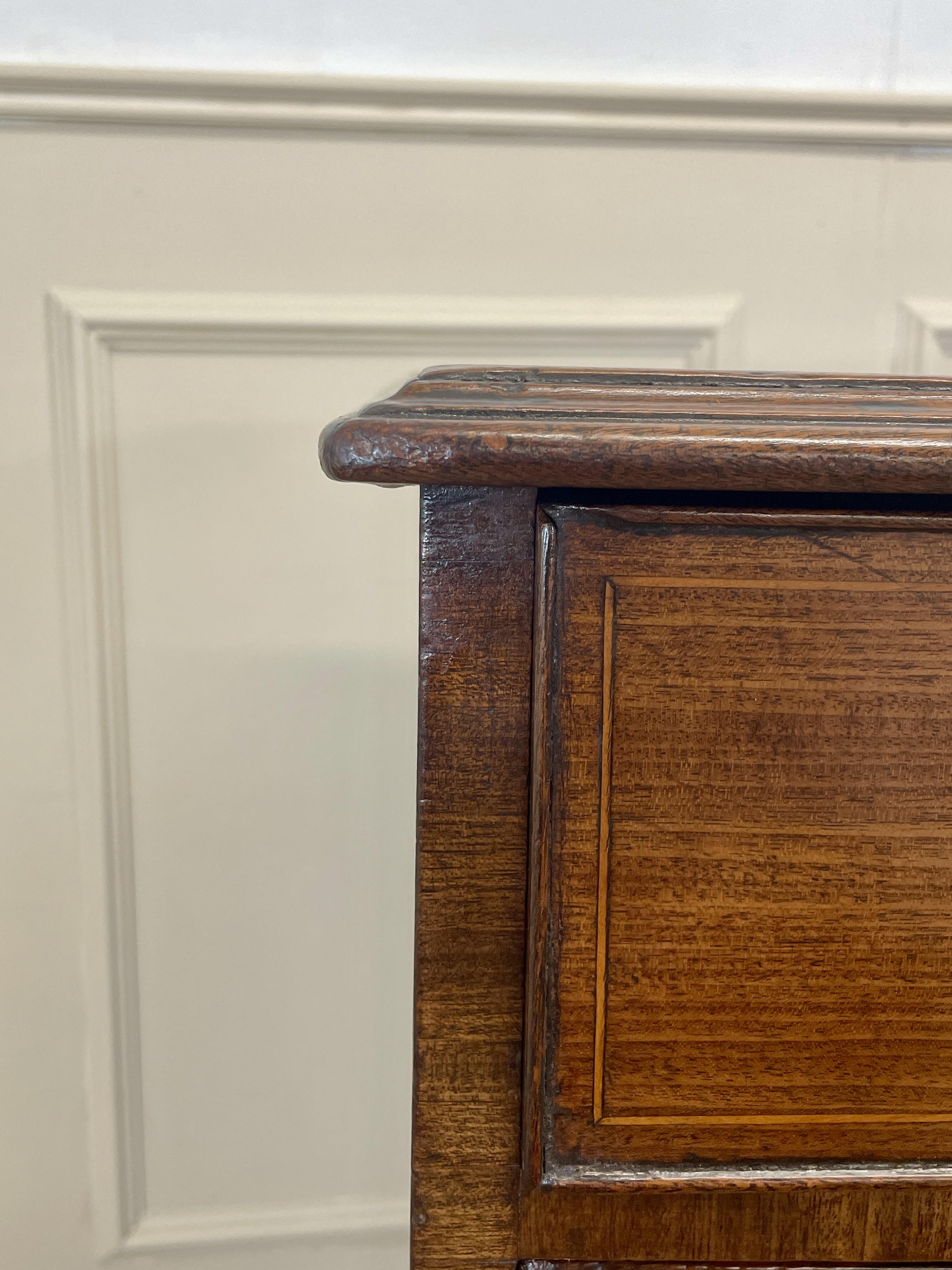 Close-up of a wooden cabinet corner with a white wall background