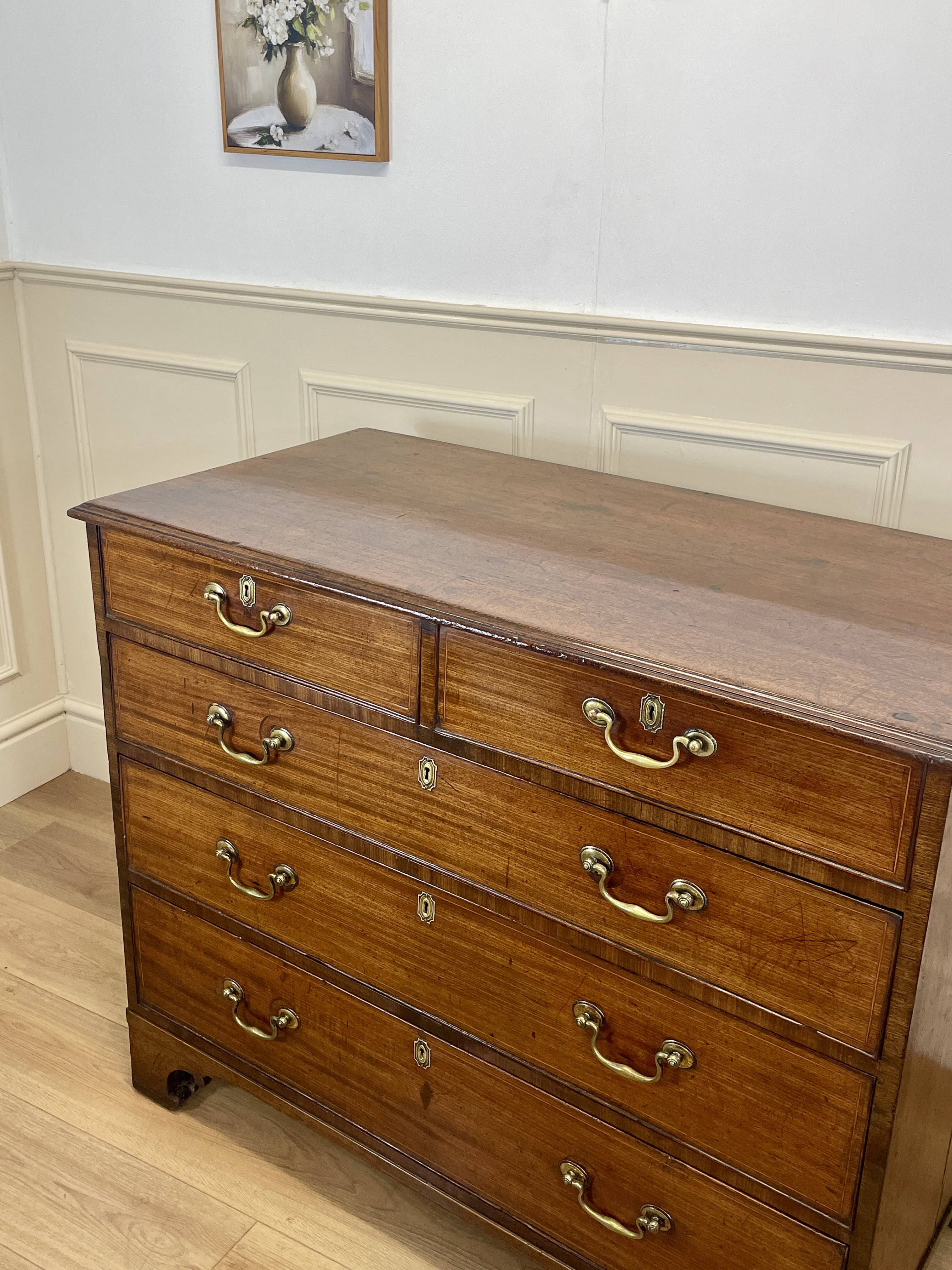 Wooden dresser with multiple drawers in a room with white walls and wooden floor.