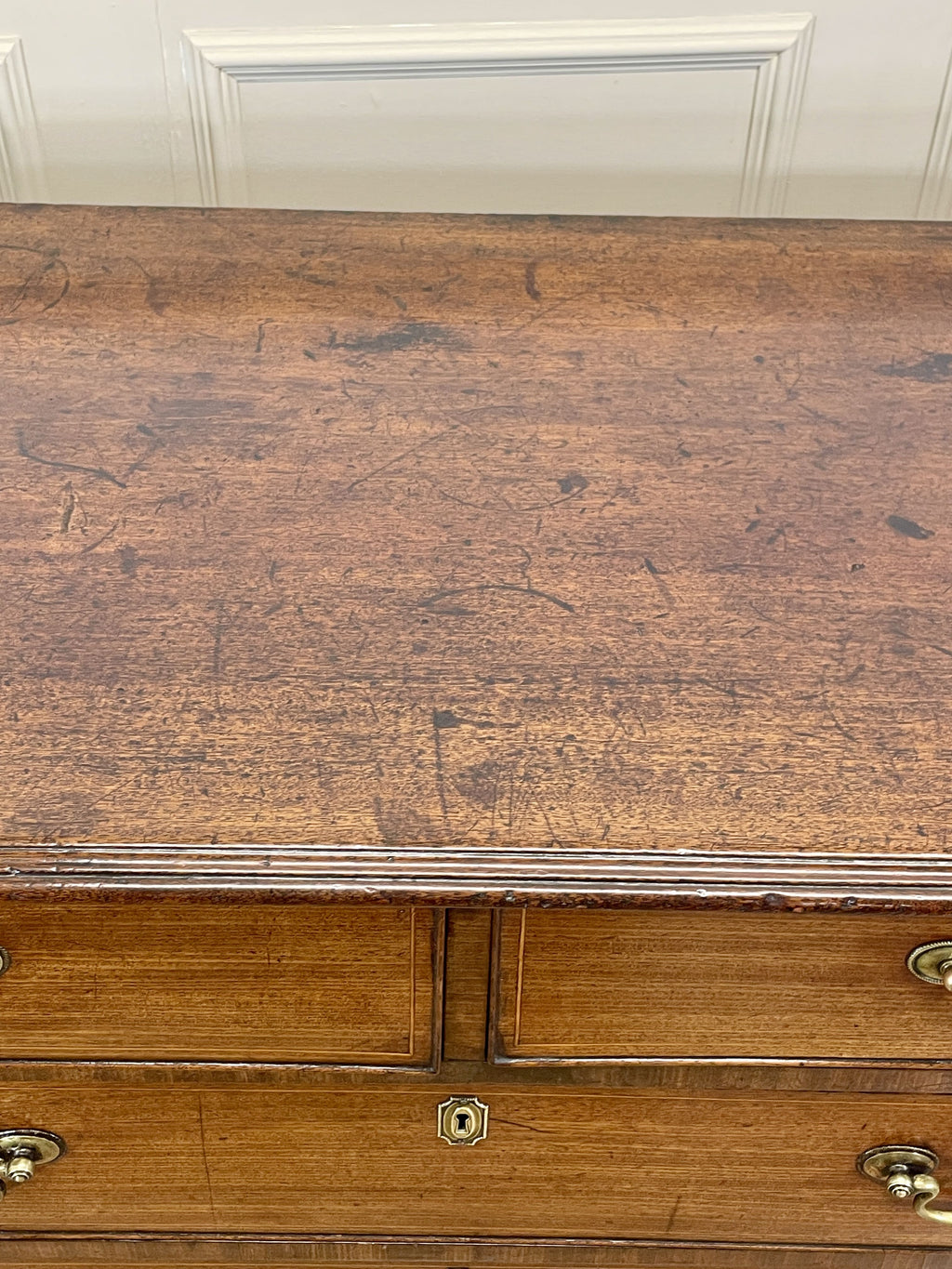 Wooden dresser with a worn surface and brass handles.