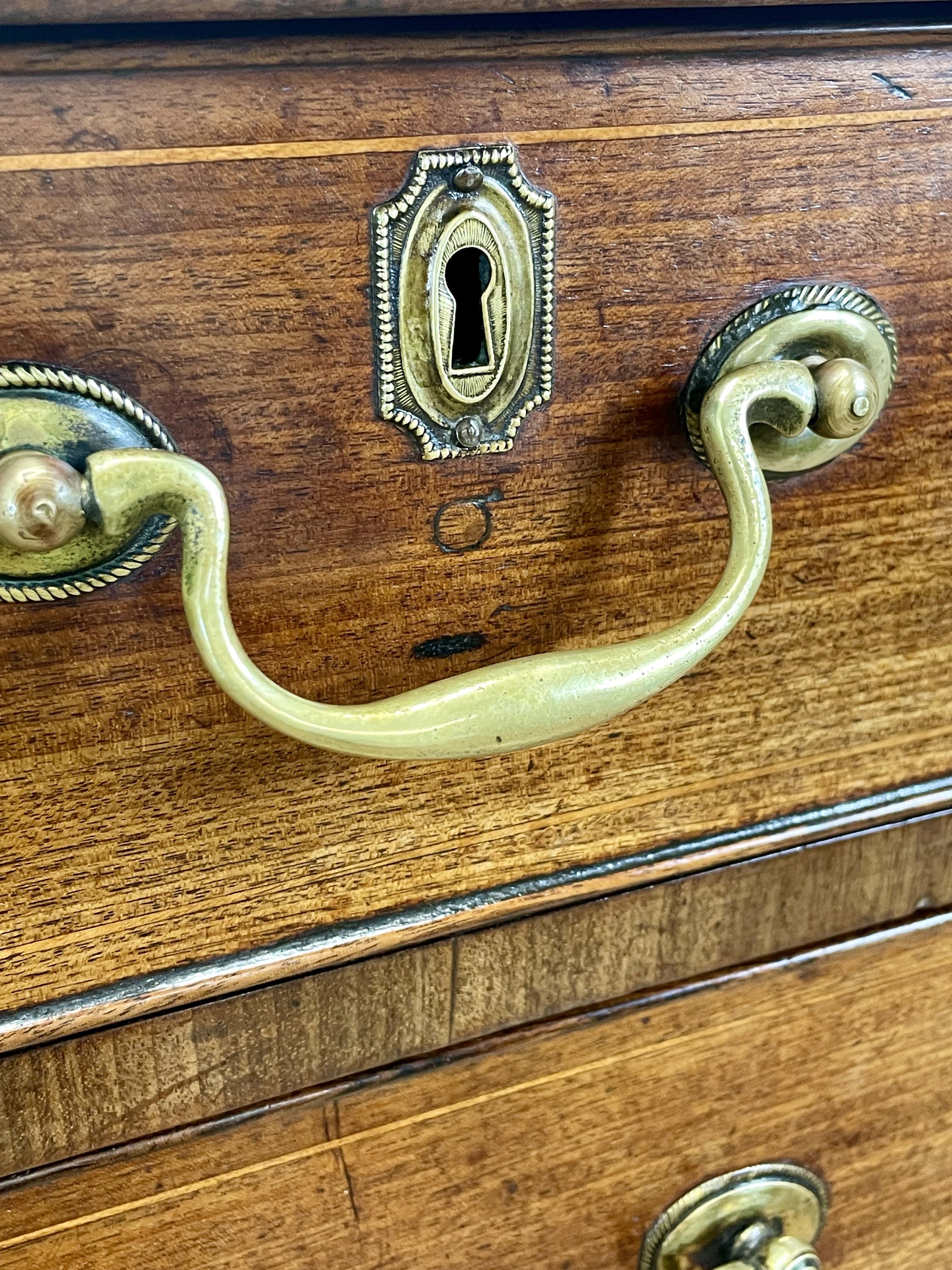 Close-up of a wooden drawer with brass handles and keyhole.