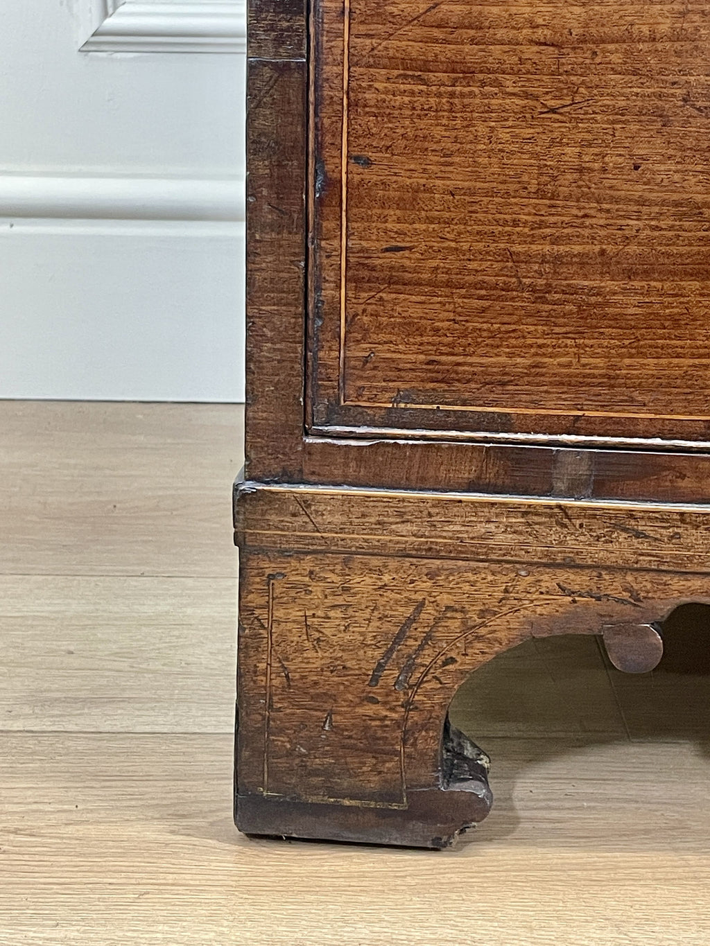 Close-up of a wooden cabinet leg on a light wood floor.