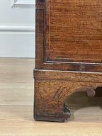 Close-up of a wooden cabinet leg on a light wood floor.