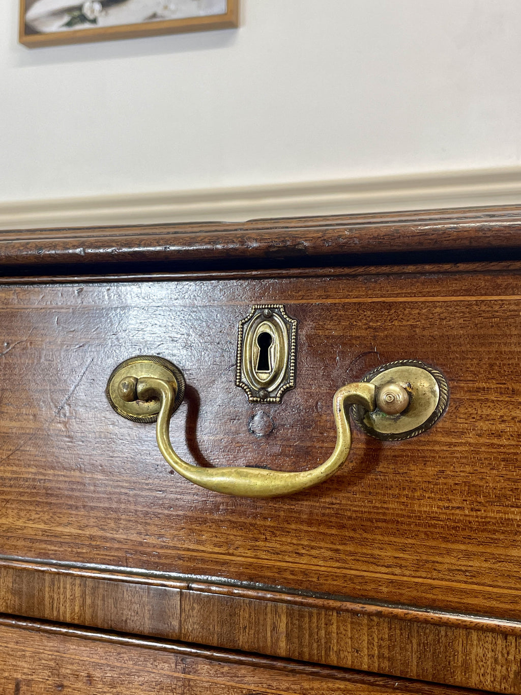 Close-up of a wooden drawer with brass handles and keyhole.