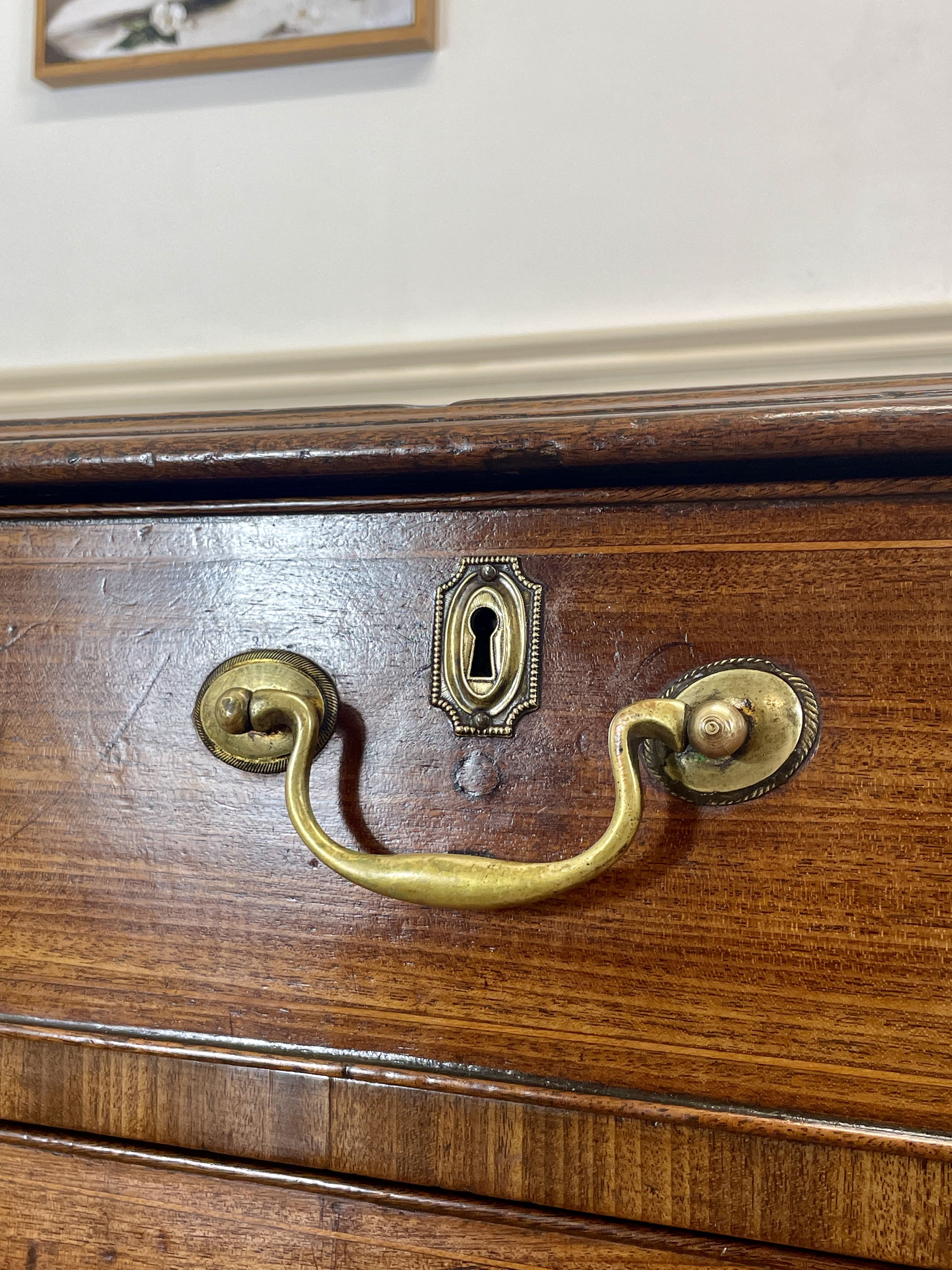 Close-up of a wooden drawer with brass handles and keyhole.