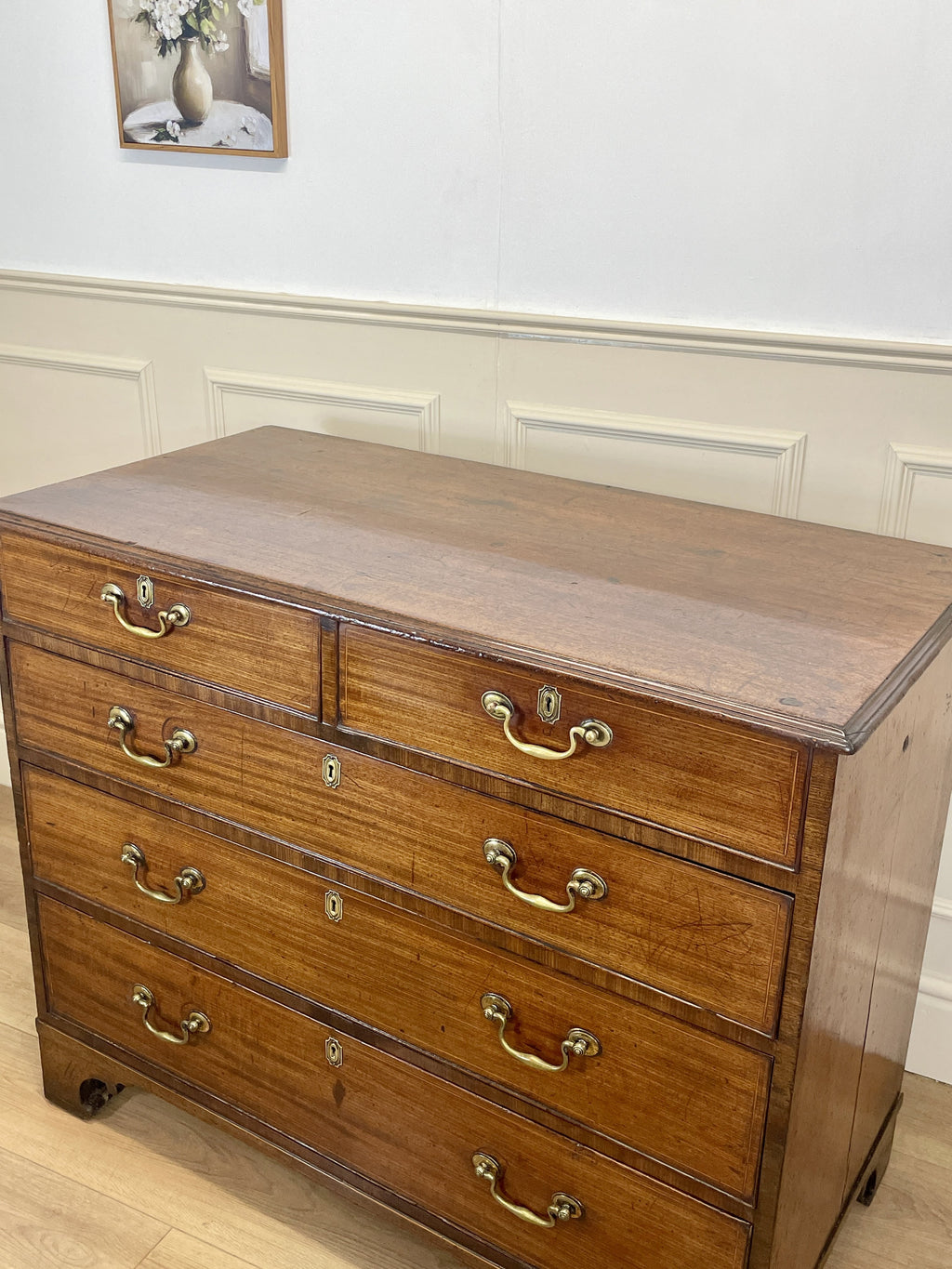 Wooden dresser with multiple drawers and brass handles in a room setting.