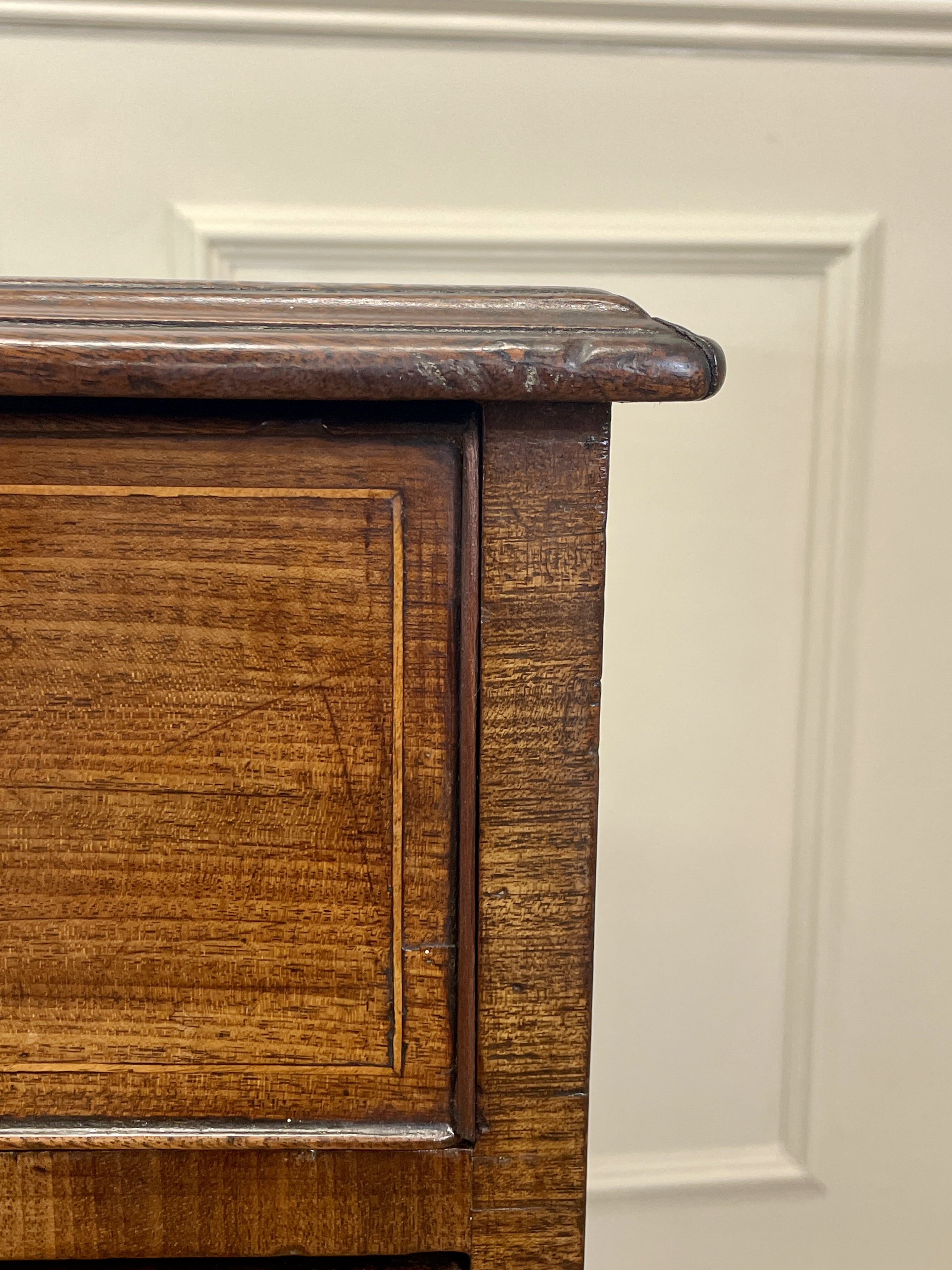 Close-up of a wooden cabinet corner with a white wall background