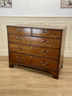 Wooden dresser with multiple drawers on a wooden floor.
