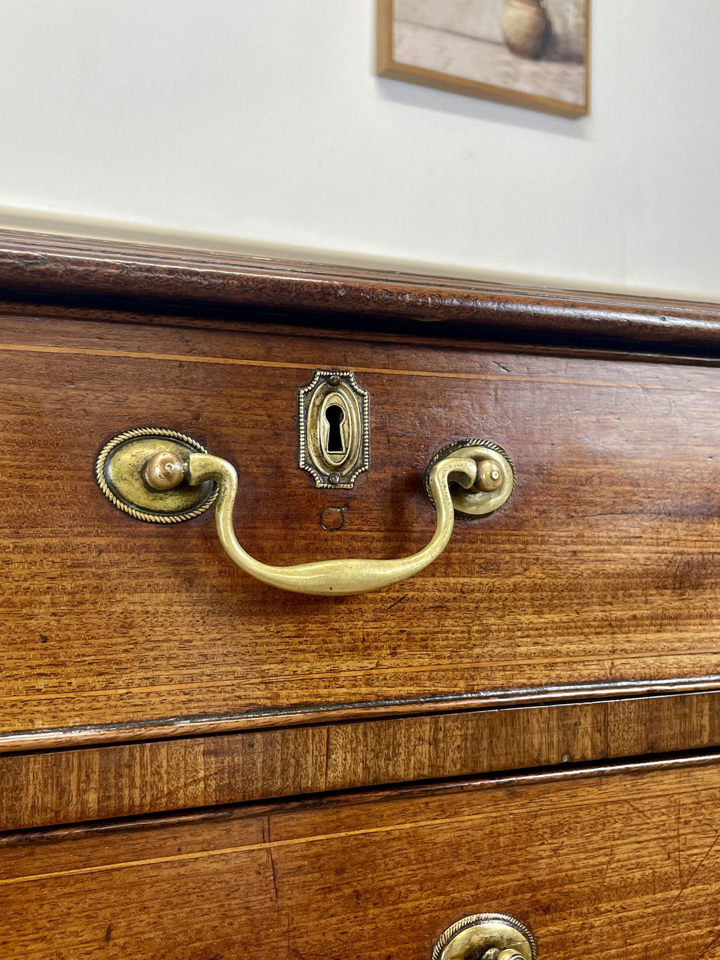 Wooden drawer with brass handle and keyhole on a white wall background