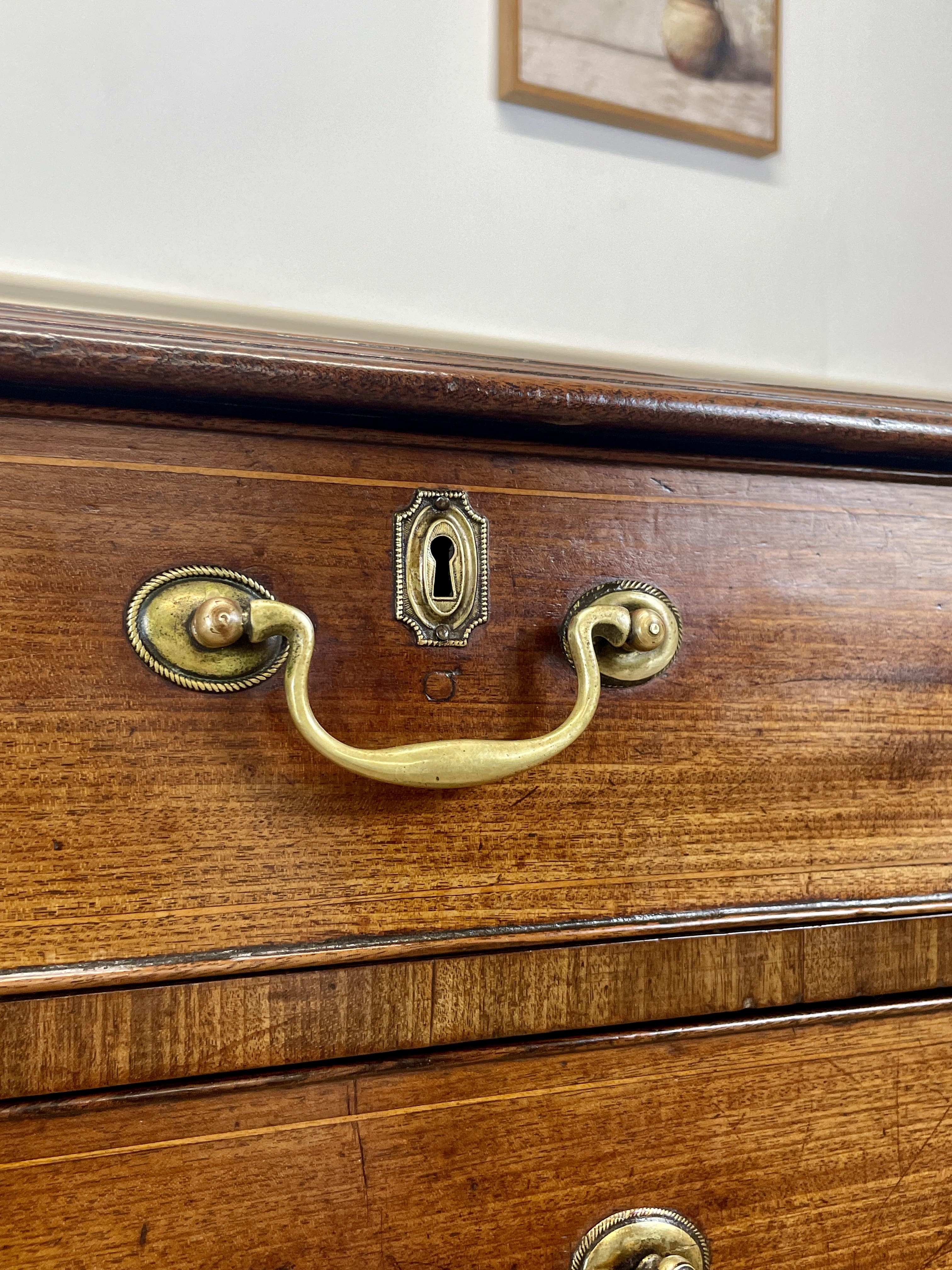 Wooden drawer with brass handle and keyhole on a white wall background