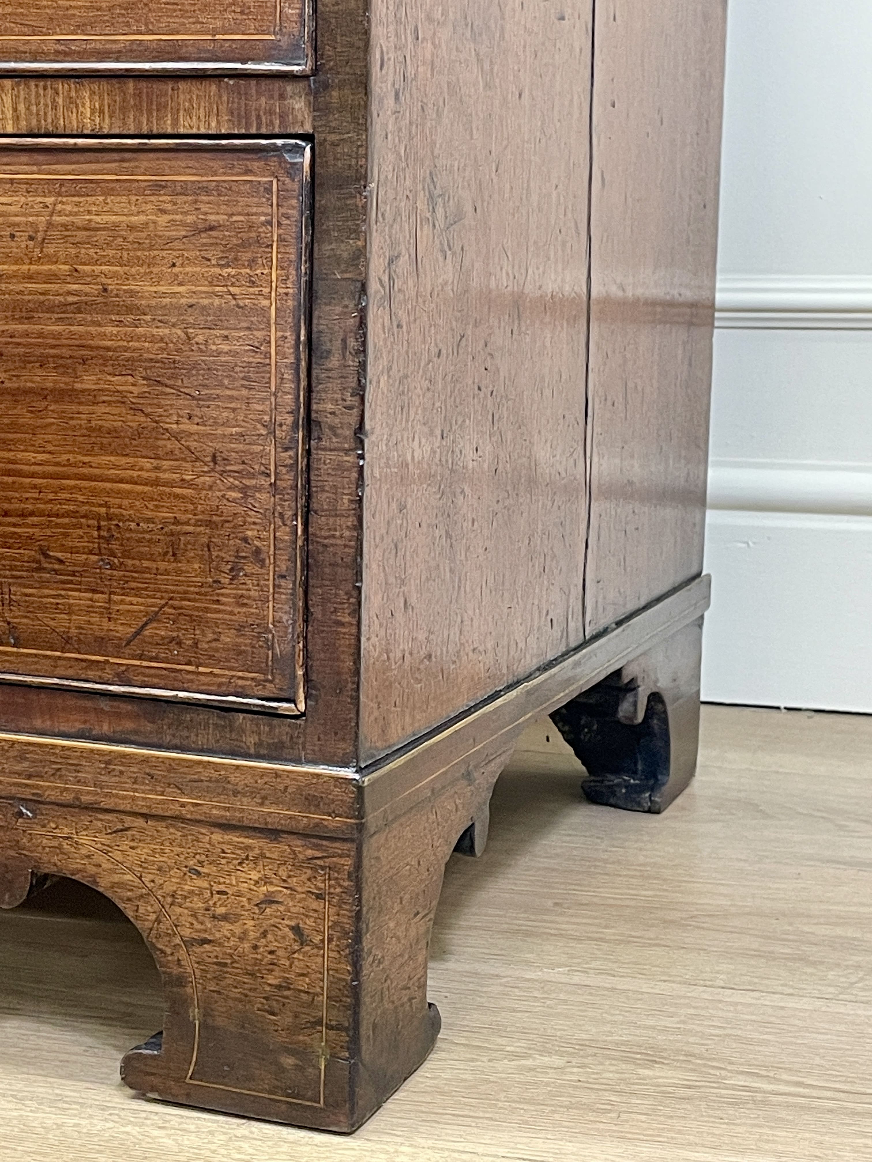 Close-up of a wooden cabinet with a white baseboard in the background