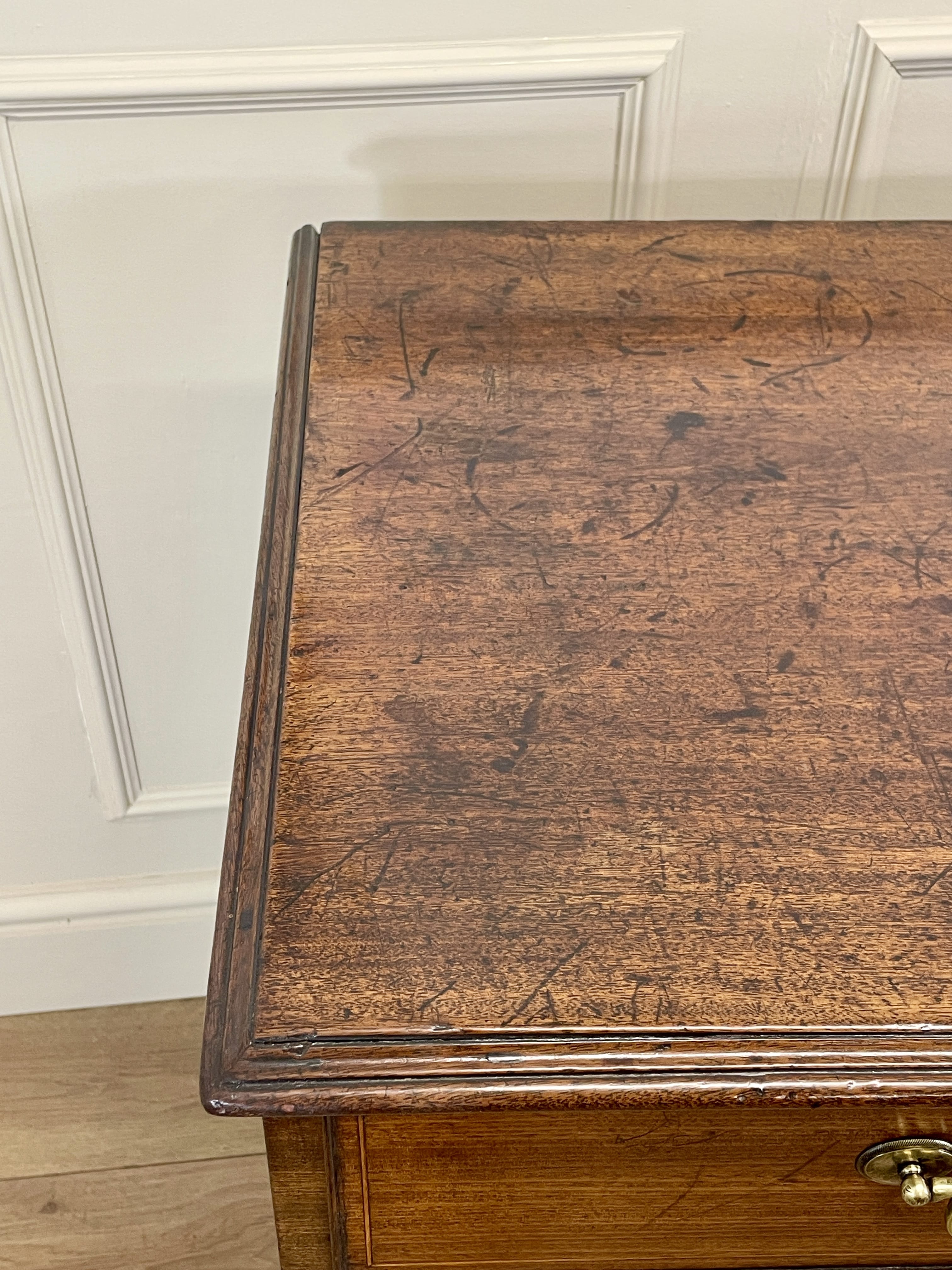 Close-up of a wooden desk with a white wall background