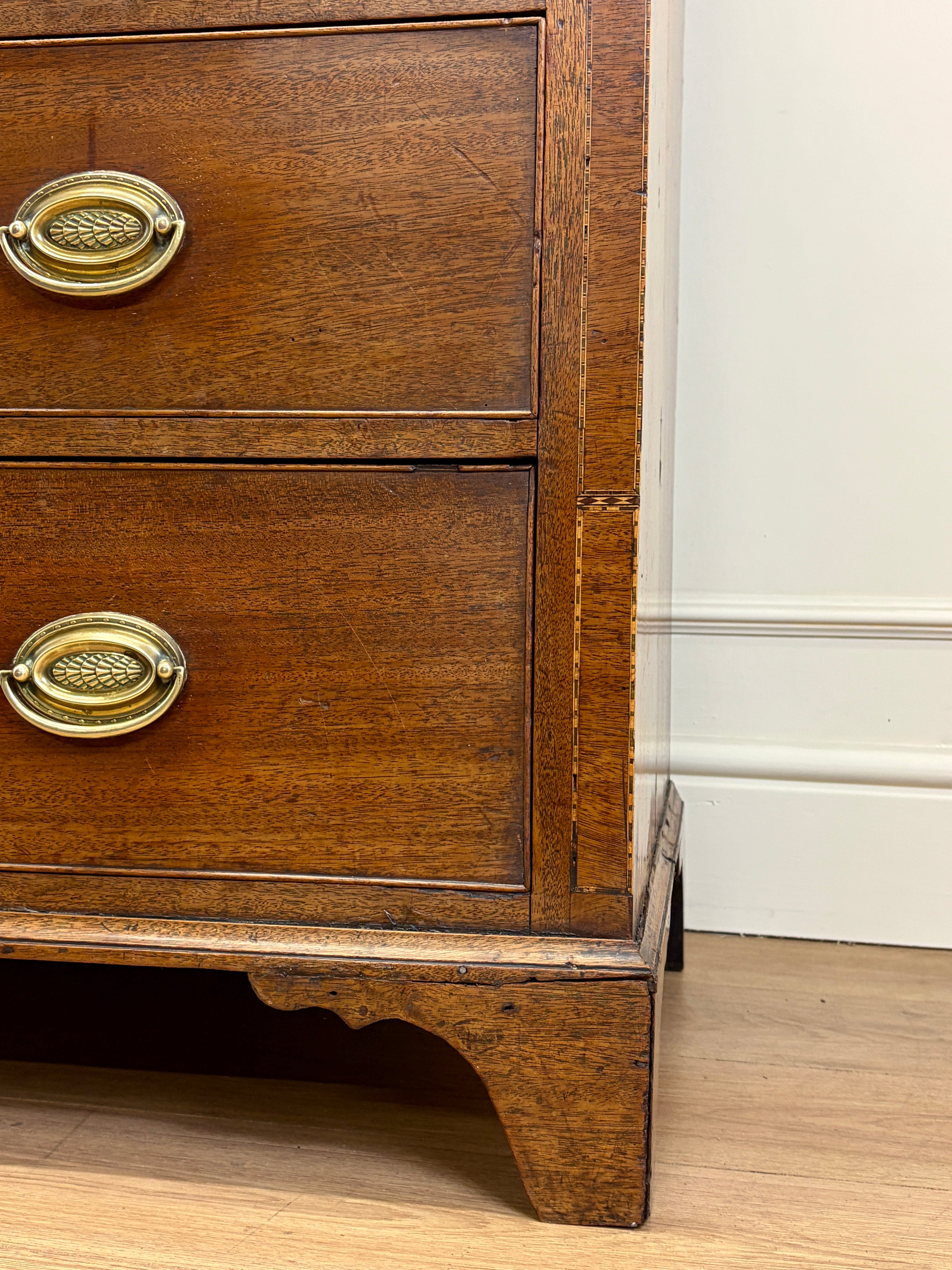 Wooden dresser with brass handles against a white wall.