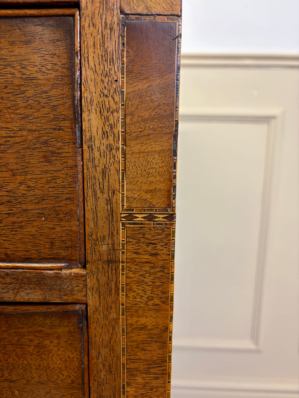 Close-up of a wooden cabinet door with a white panel in the background