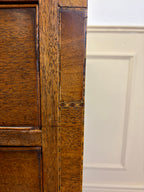 Close-up of a wooden cabinet door with a white panel in the background