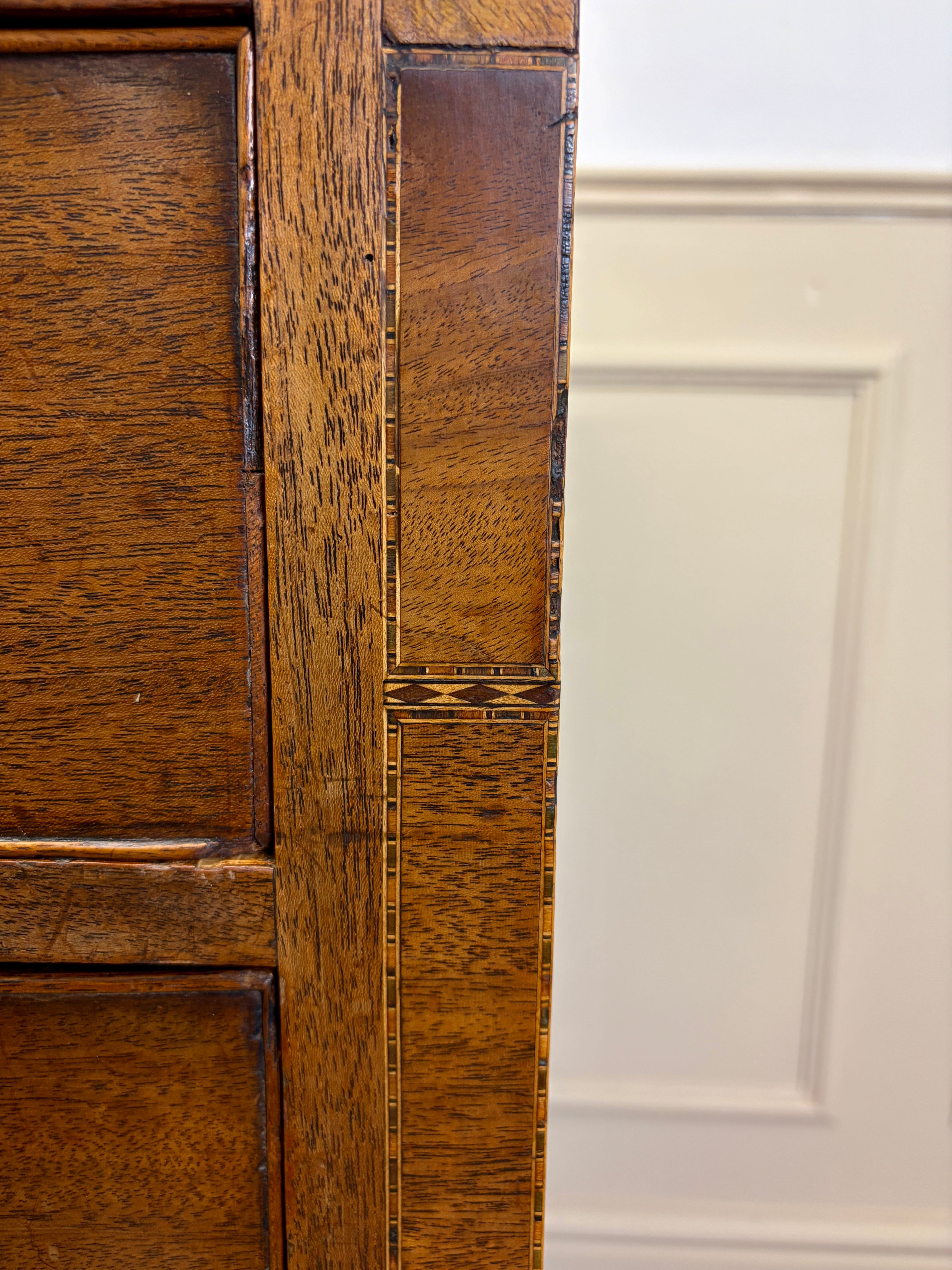 Close-up of a wooden cabinet door with a white panel in the background