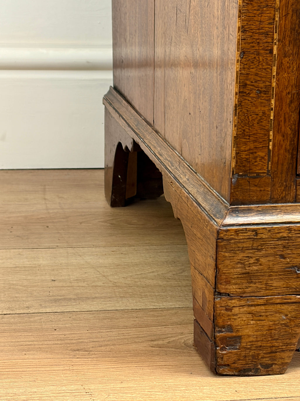 Close-up of a wooden cabinet corner on a wooden floor.
