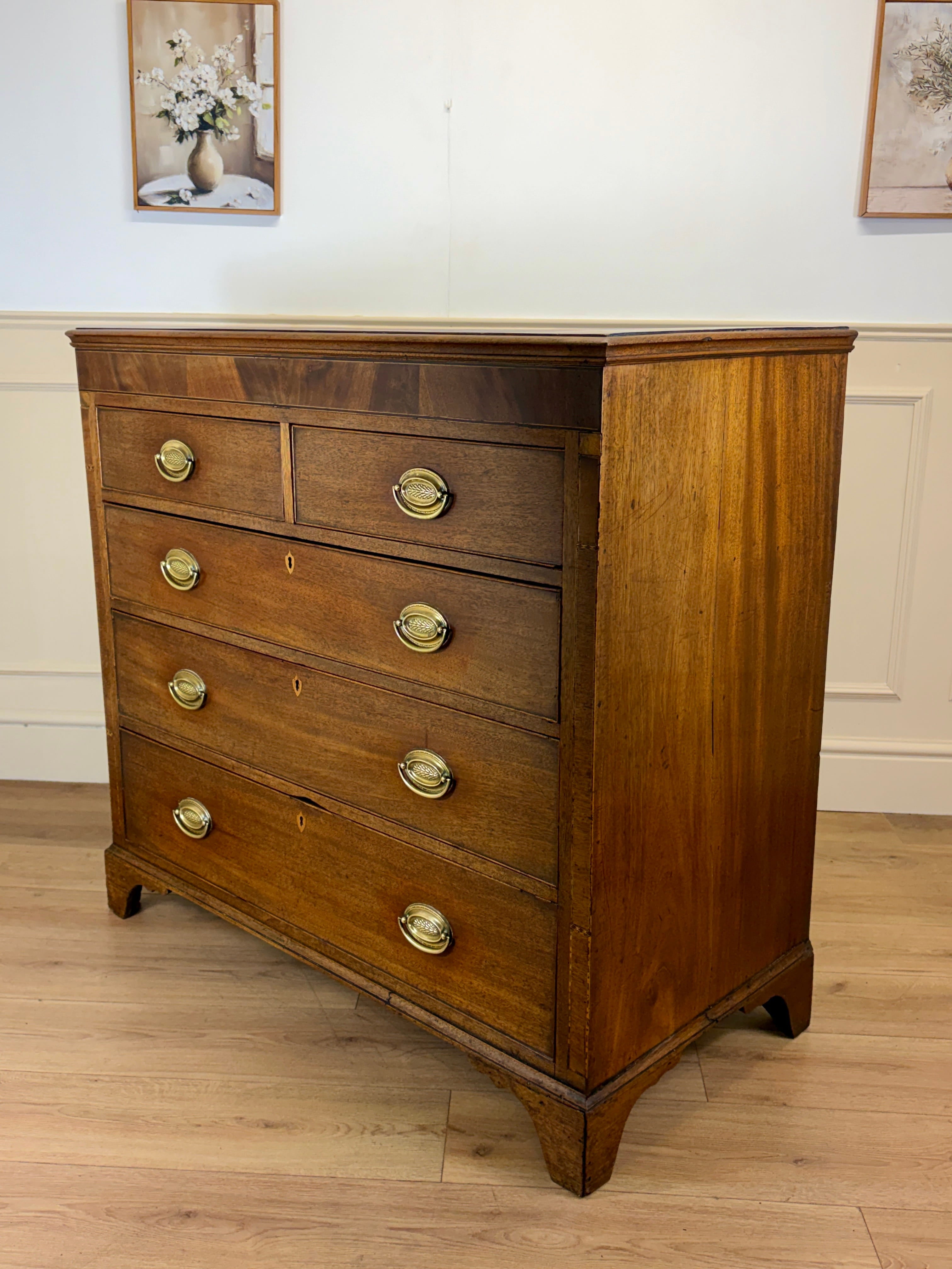 Wooden dresser with brass handles on a wooden floor.