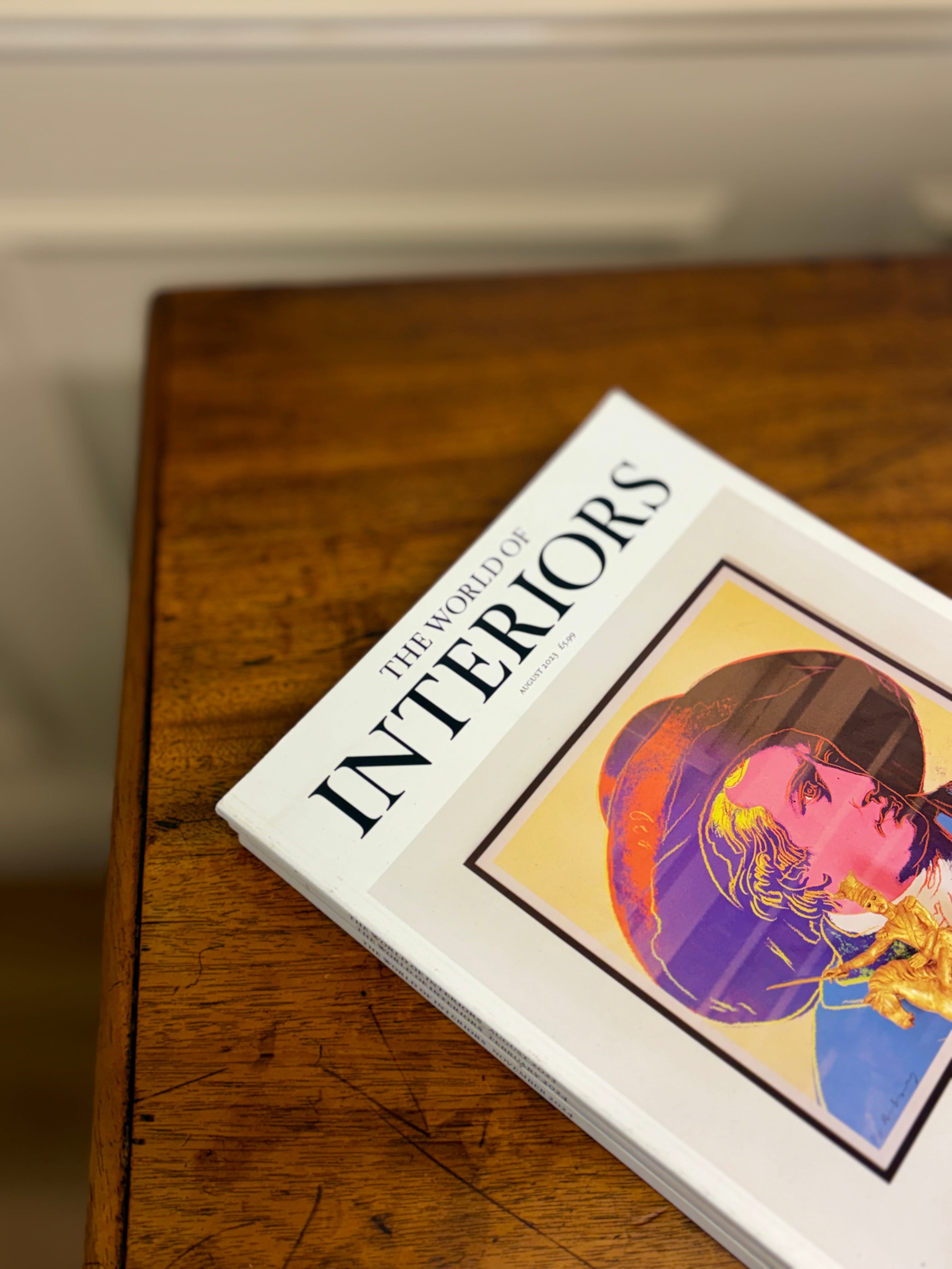 Book titled 'The World of Interiors' on a wooden surface