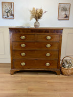 Wooden dresser with gold handles in a room with framed pictures and a basket.