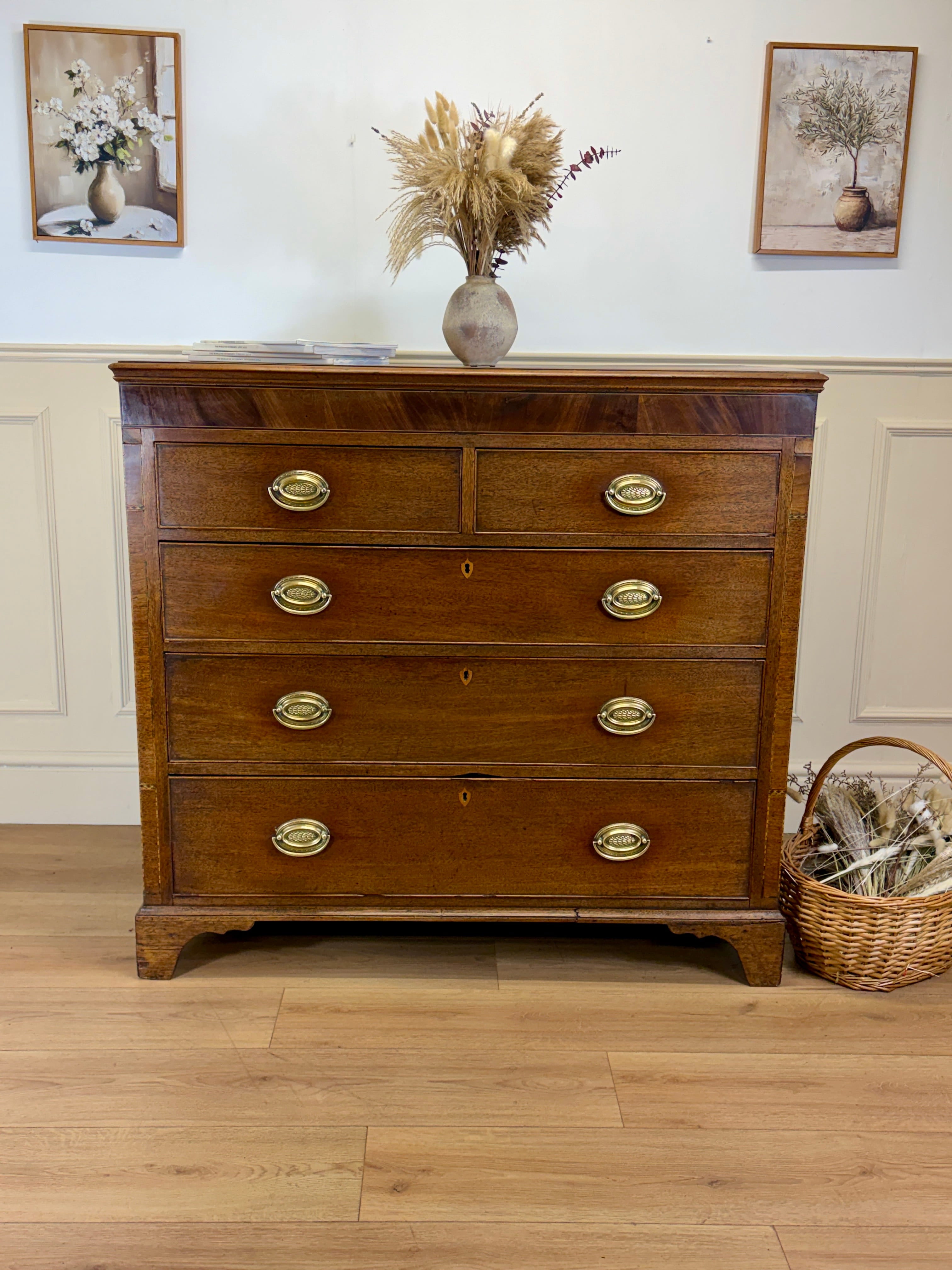 Wooden dresser with gold handles in a room with framed pictures and a basket.