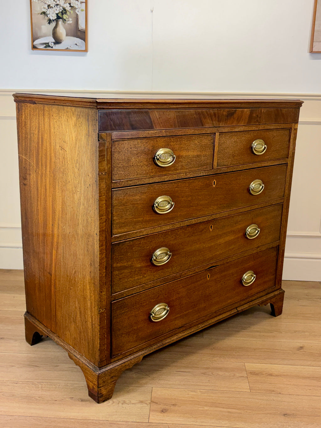 Wooden dresser with gold handles on a wooden floor.