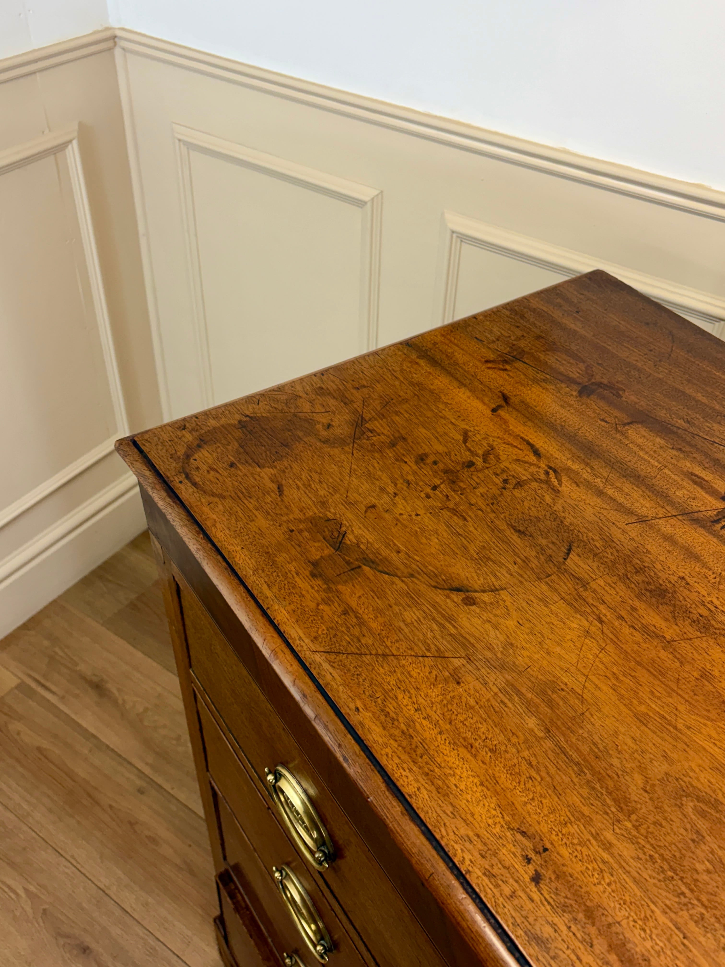 Wooden dresser with a gold handle against a white paneled wall.