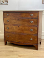 Wooden dresser with four drawers on a wooden floor.