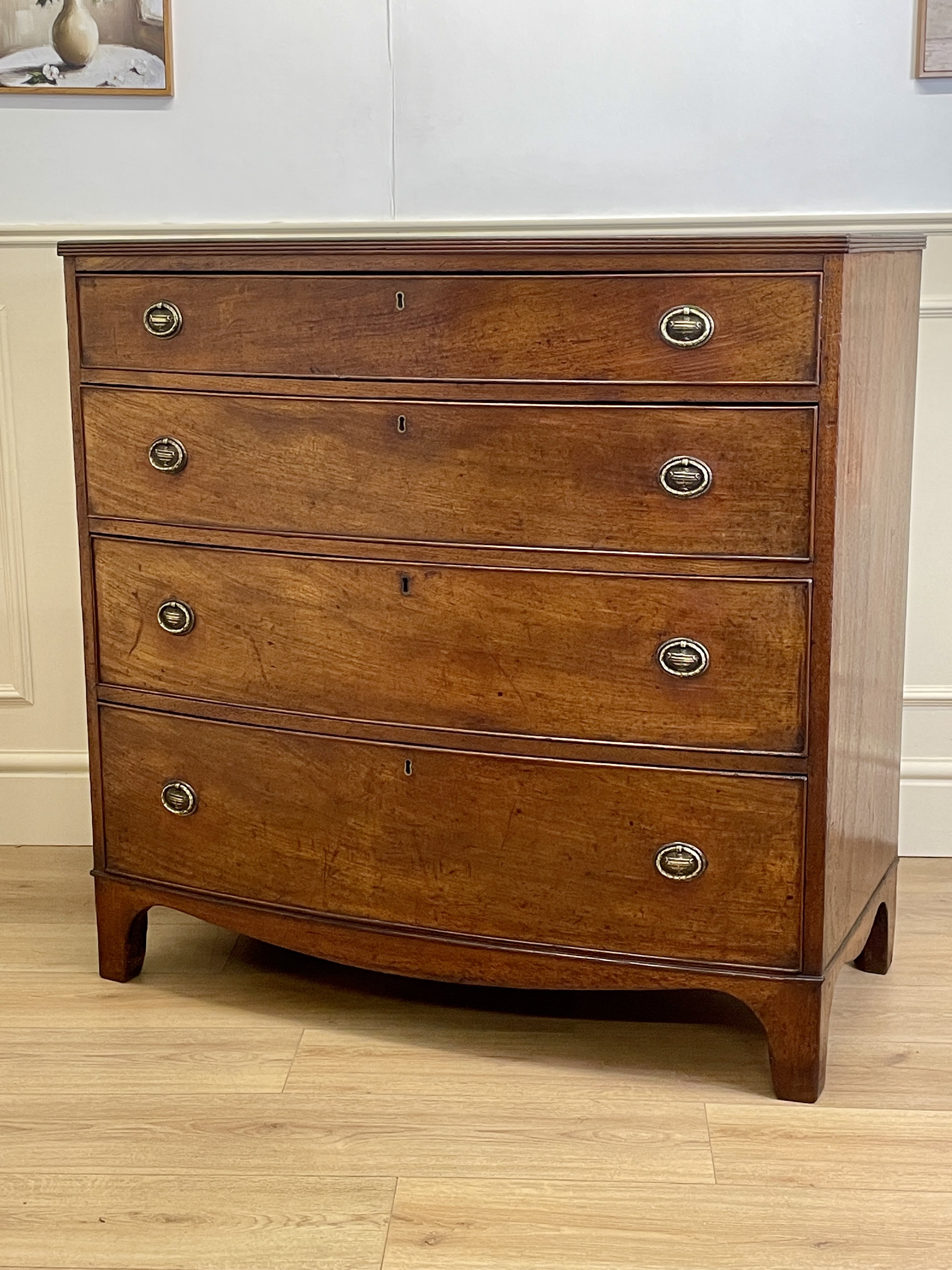 Wooden dresser with four drawers on a wooden floor.