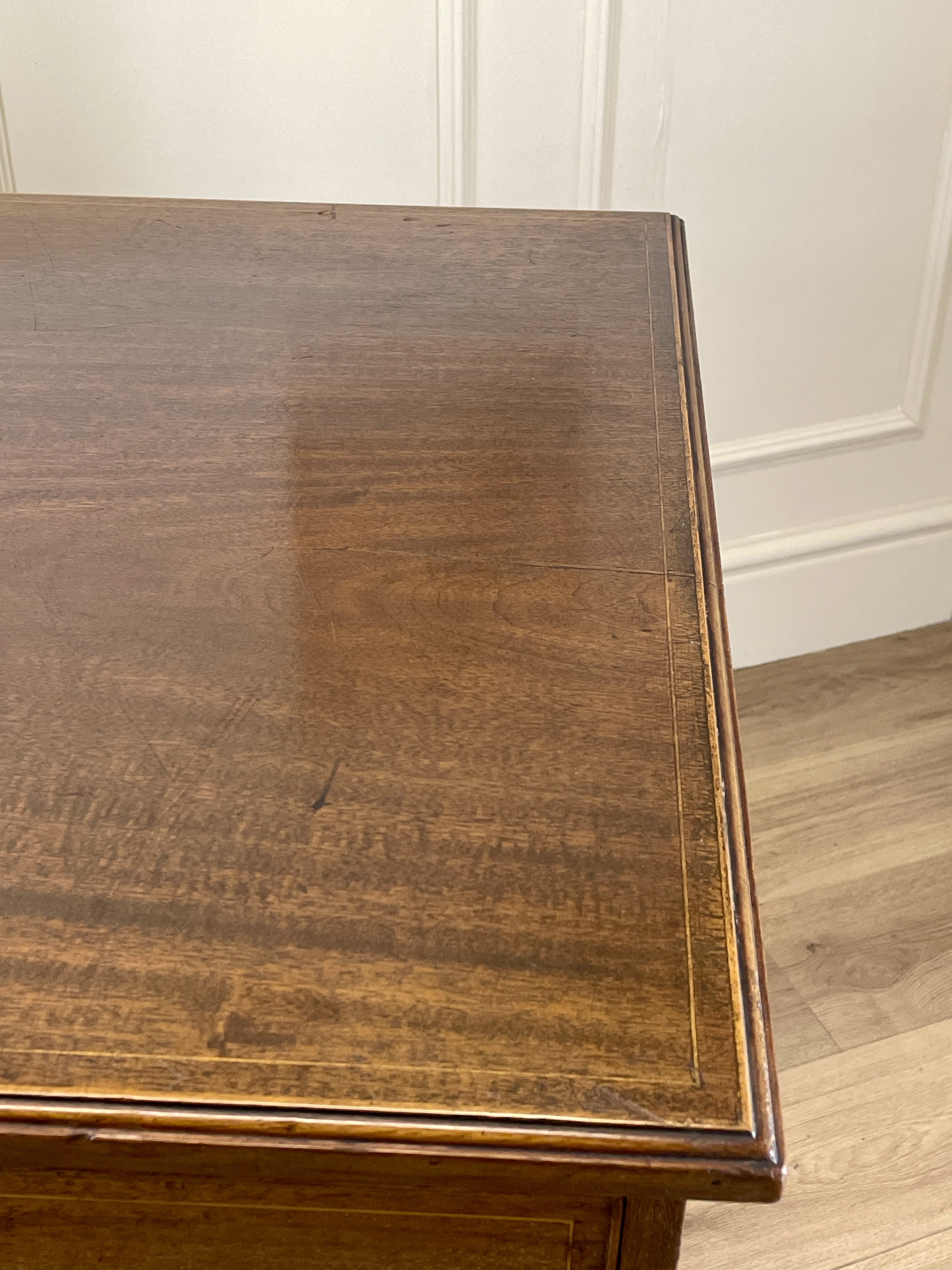 Wooden table with a smooth surface against a white paneled wall.