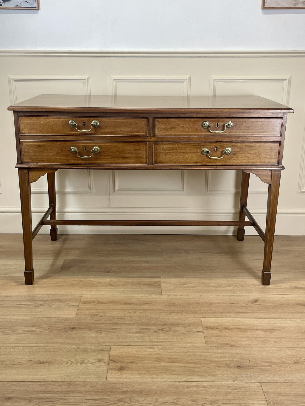 Wooden dresser with four drawers on a wooden floor against a white wall.
