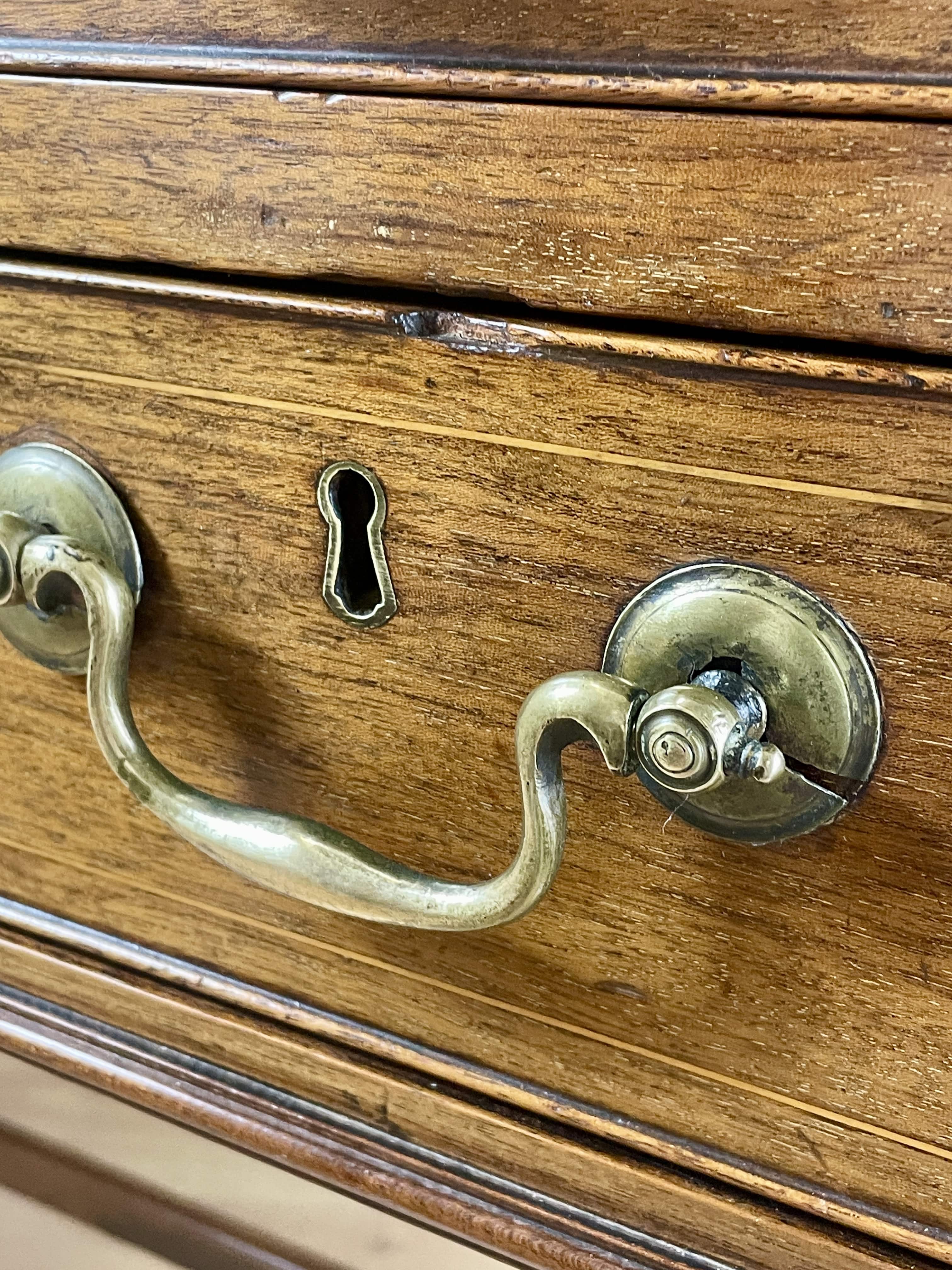 Close-up of a wooden drawer with brass handles and keyhole.