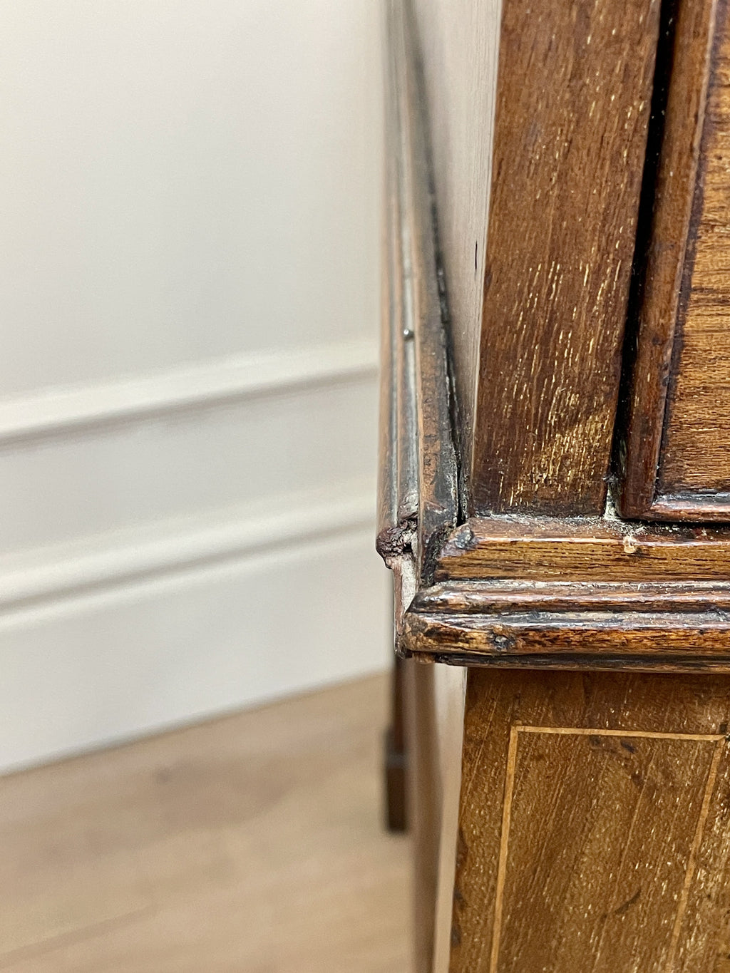Close-up of a wooden cabinet corner with a white wall background