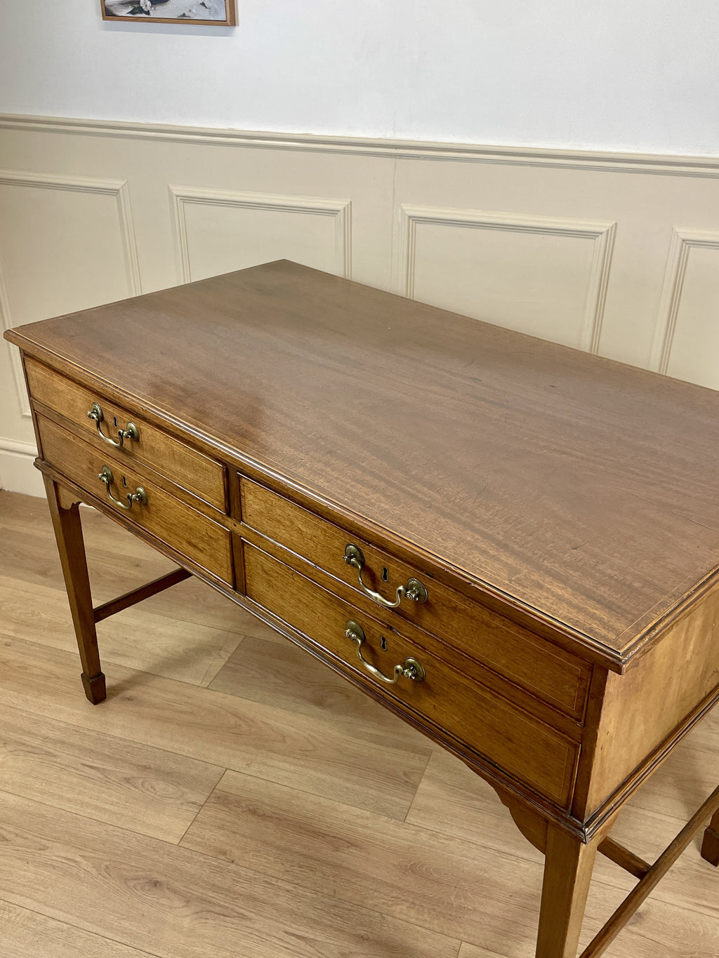 Wooden desk with drawers in a room with panelled walls.