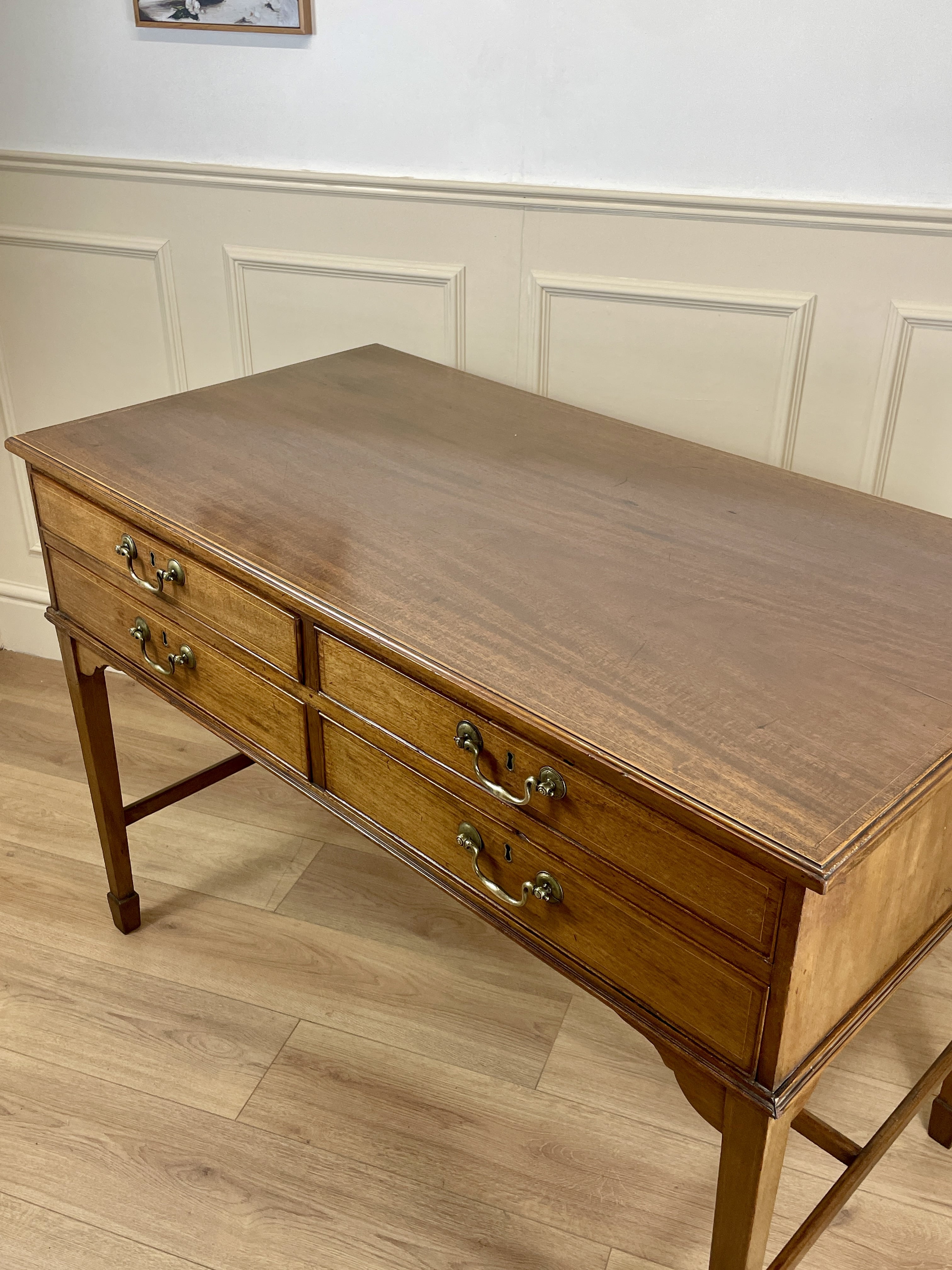 Wooden desk with drawers in a room with panelled walls.