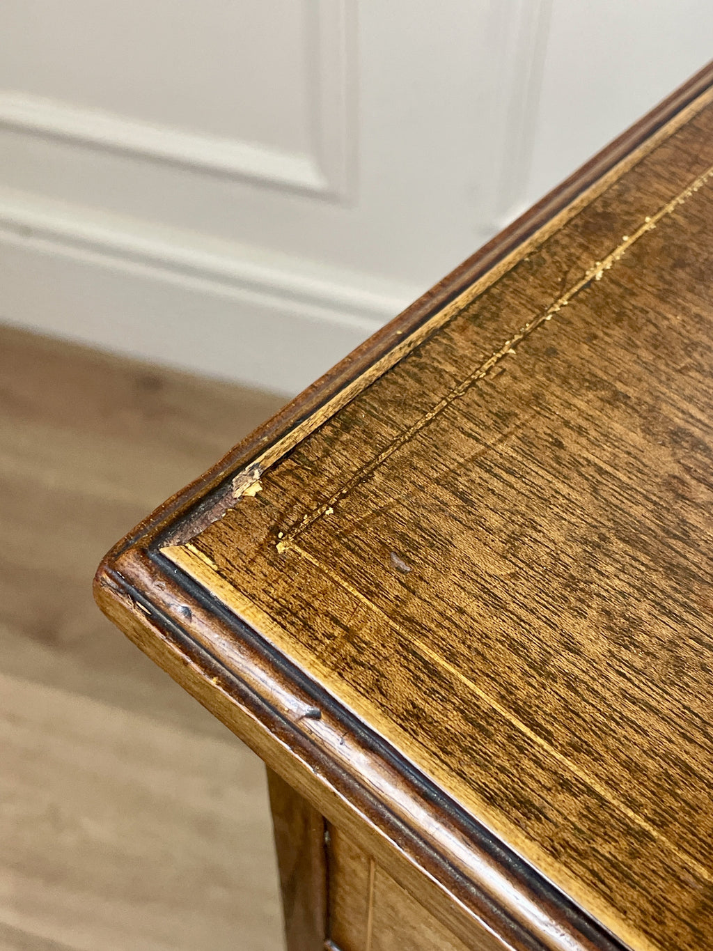 Close-up of a wooden table corner with visible wear and tear.