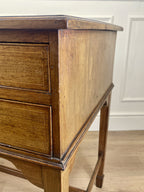 Wooden desk with two drawers against a white wall.