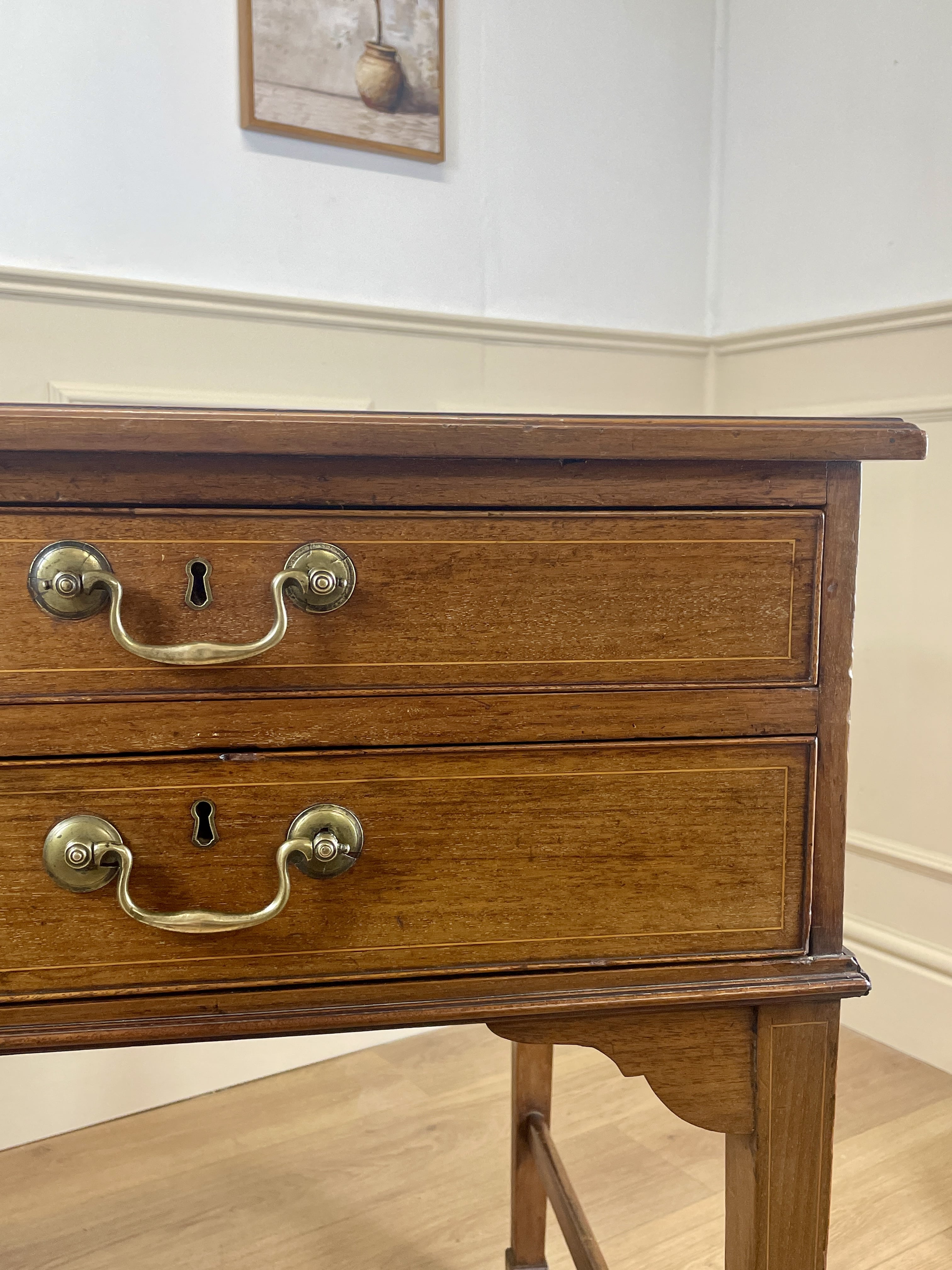 Wooden dresser with brass handles on a light wooden floor.