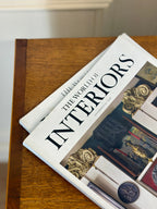 Book titled 'The World of Interiors' on a wooden surface