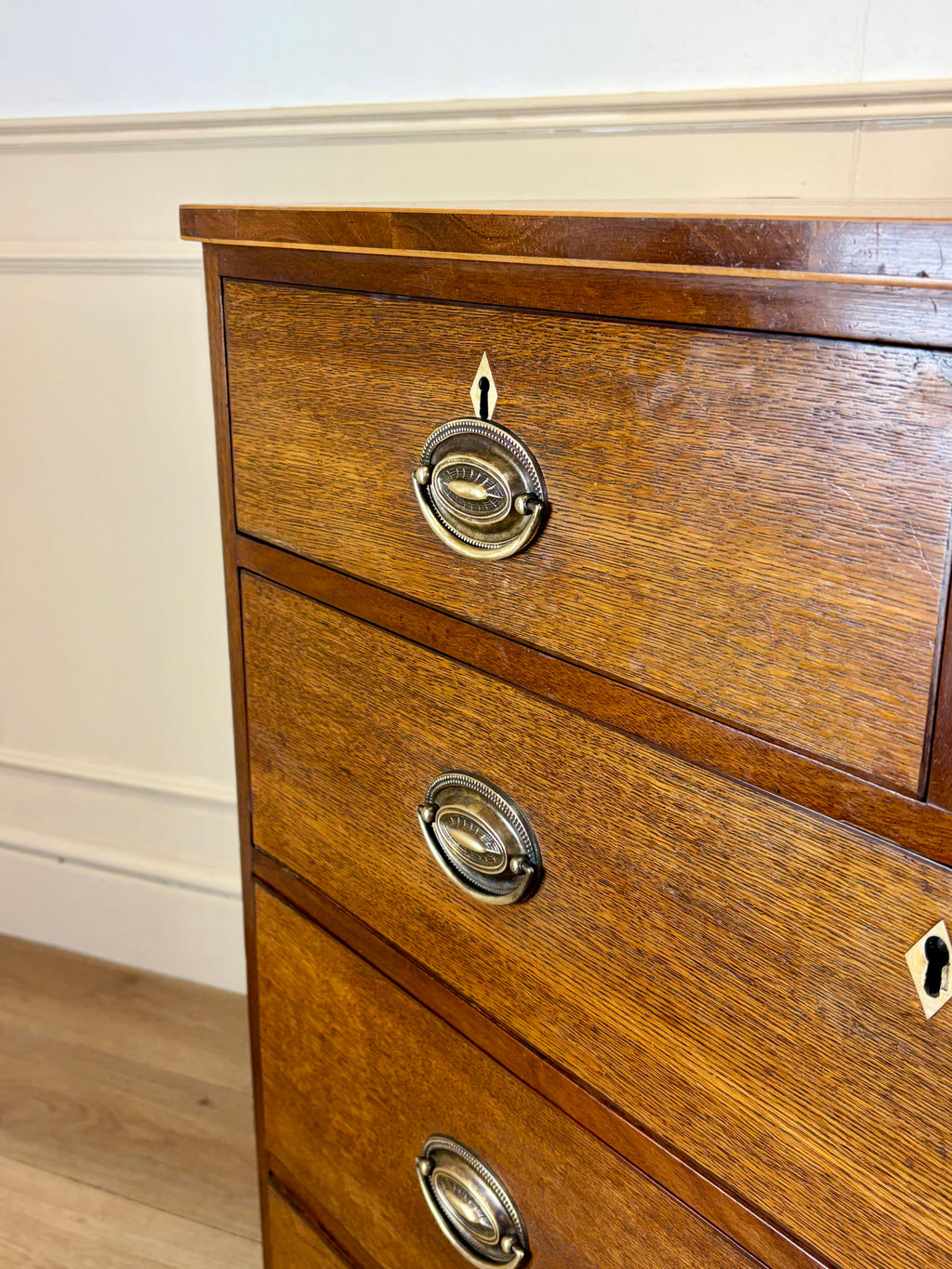 Wooden dresser with brass handles on a white wall background