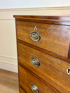 Wooden dresser with brass handles on a white wall background