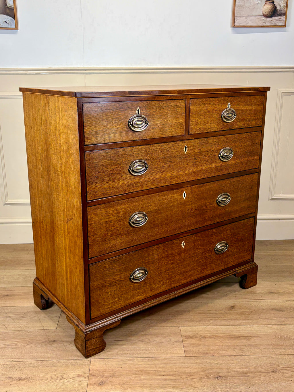 Wooden dresser with four drawers on a wooden floor.