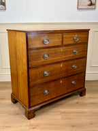 Wooden dresser with four drawers on a wooden floor.