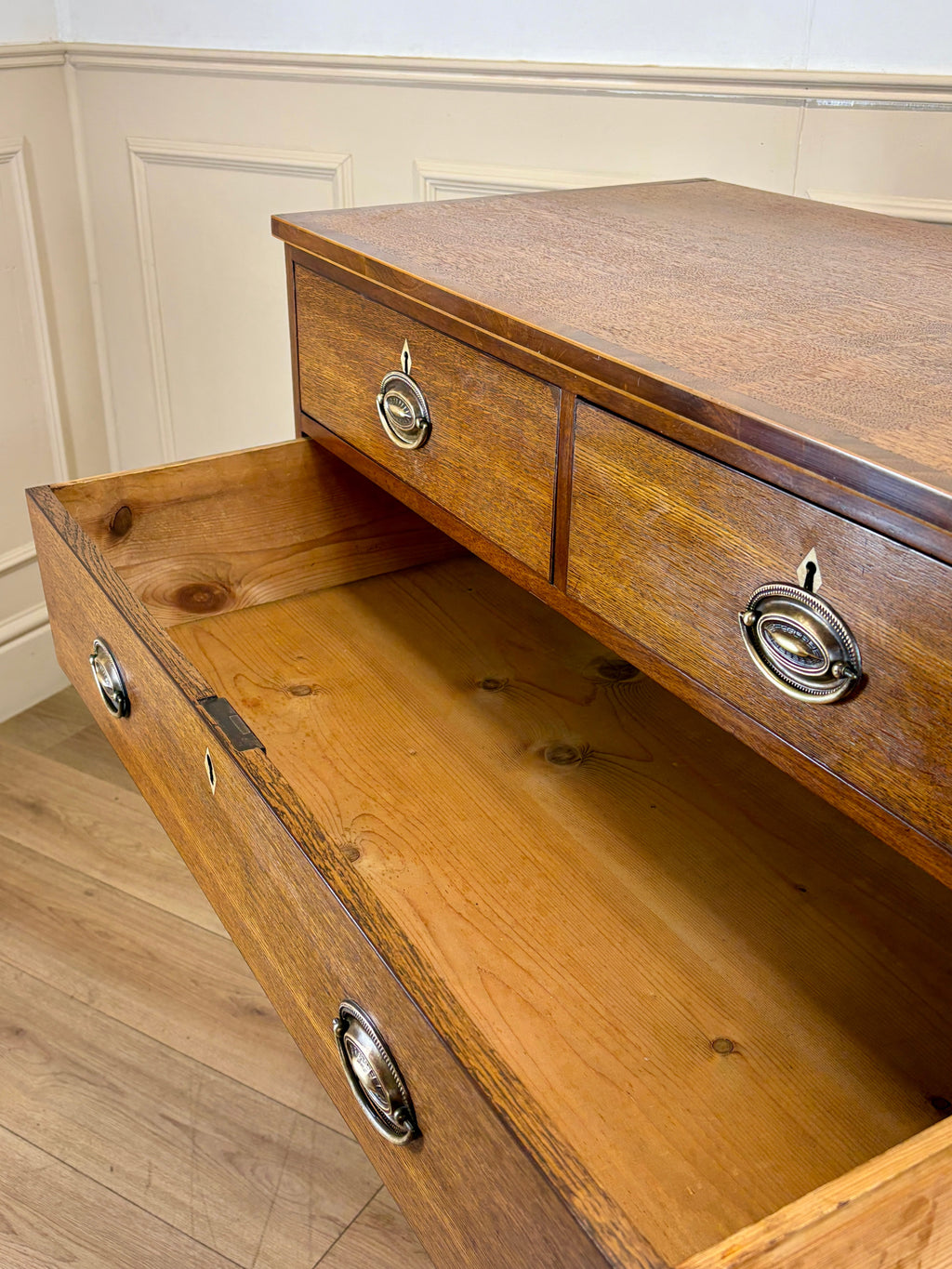 Wooden dresser with open drawer against a white wall.