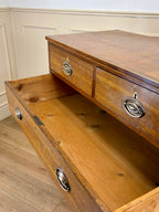 Wooden dresser with open drawer against a white wall.