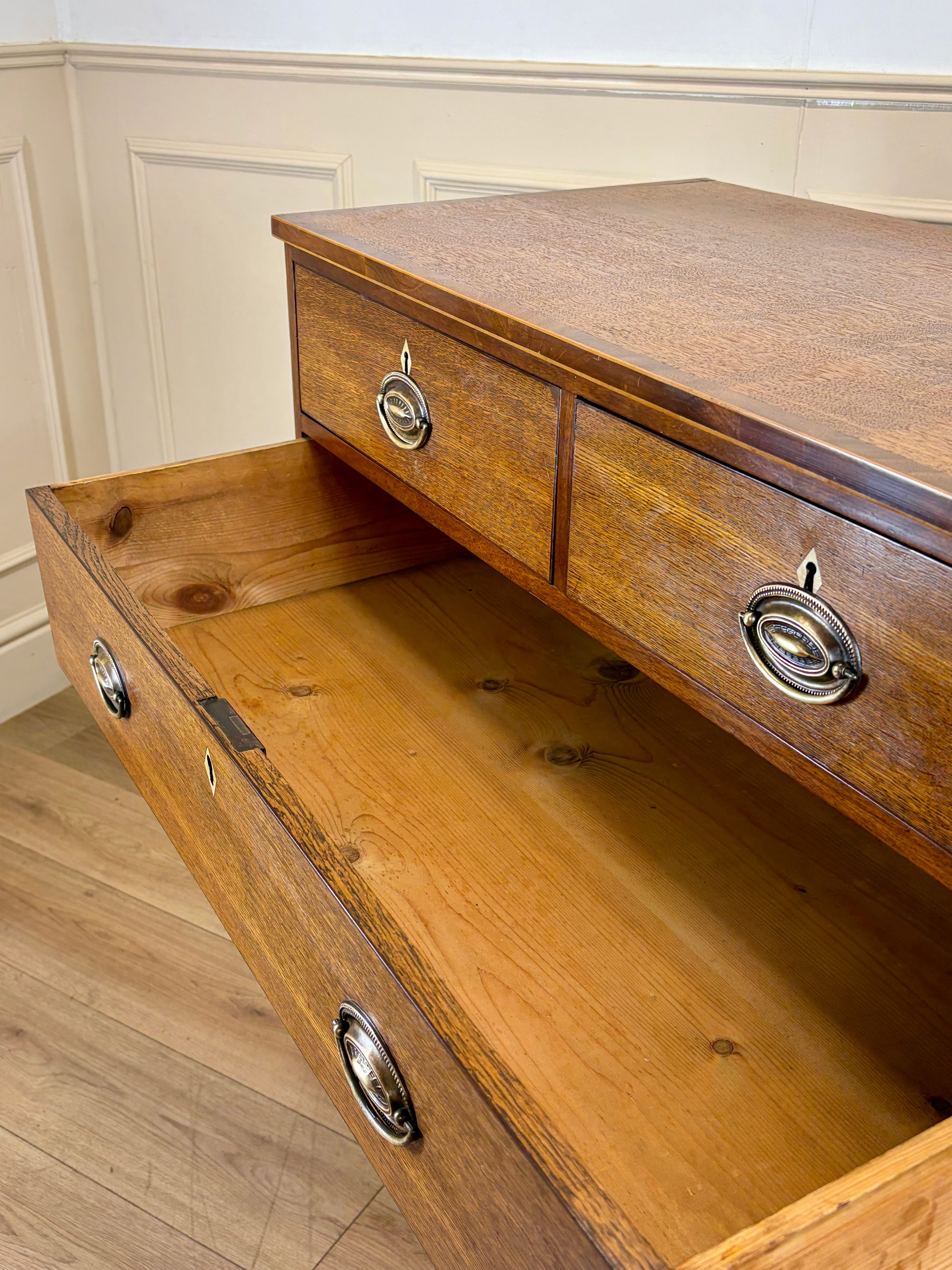 Wooden dresser with open drawer against a white wall.