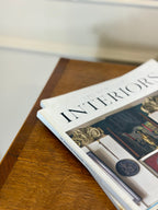 Stack of interior design magazines on a wooden surface