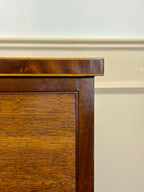 Close-up of a wooden cabinet corner with a plain wall background